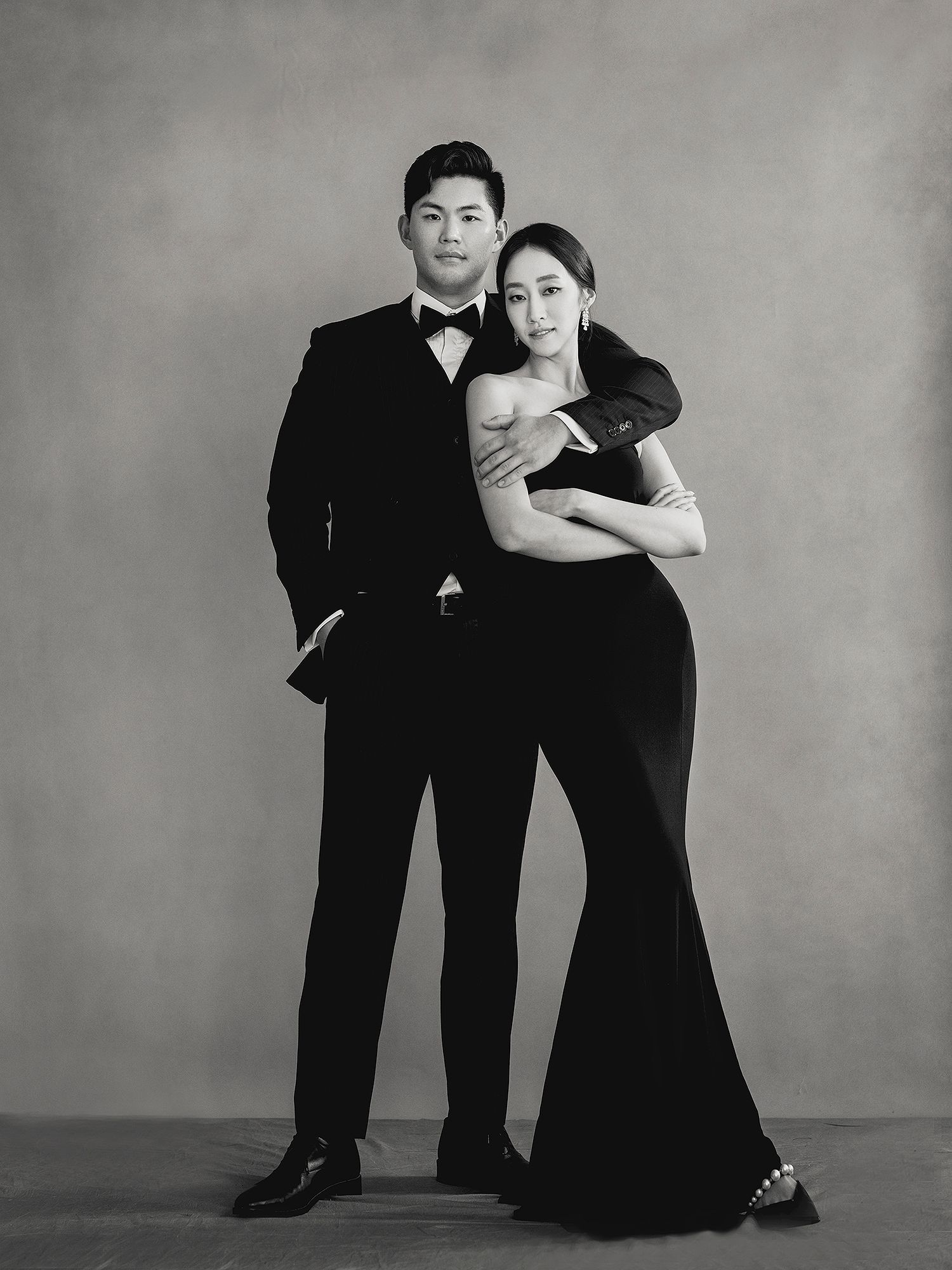Black and white artistic photo series showing figures in formal attire striking dramatic poses against a plain backdrop.