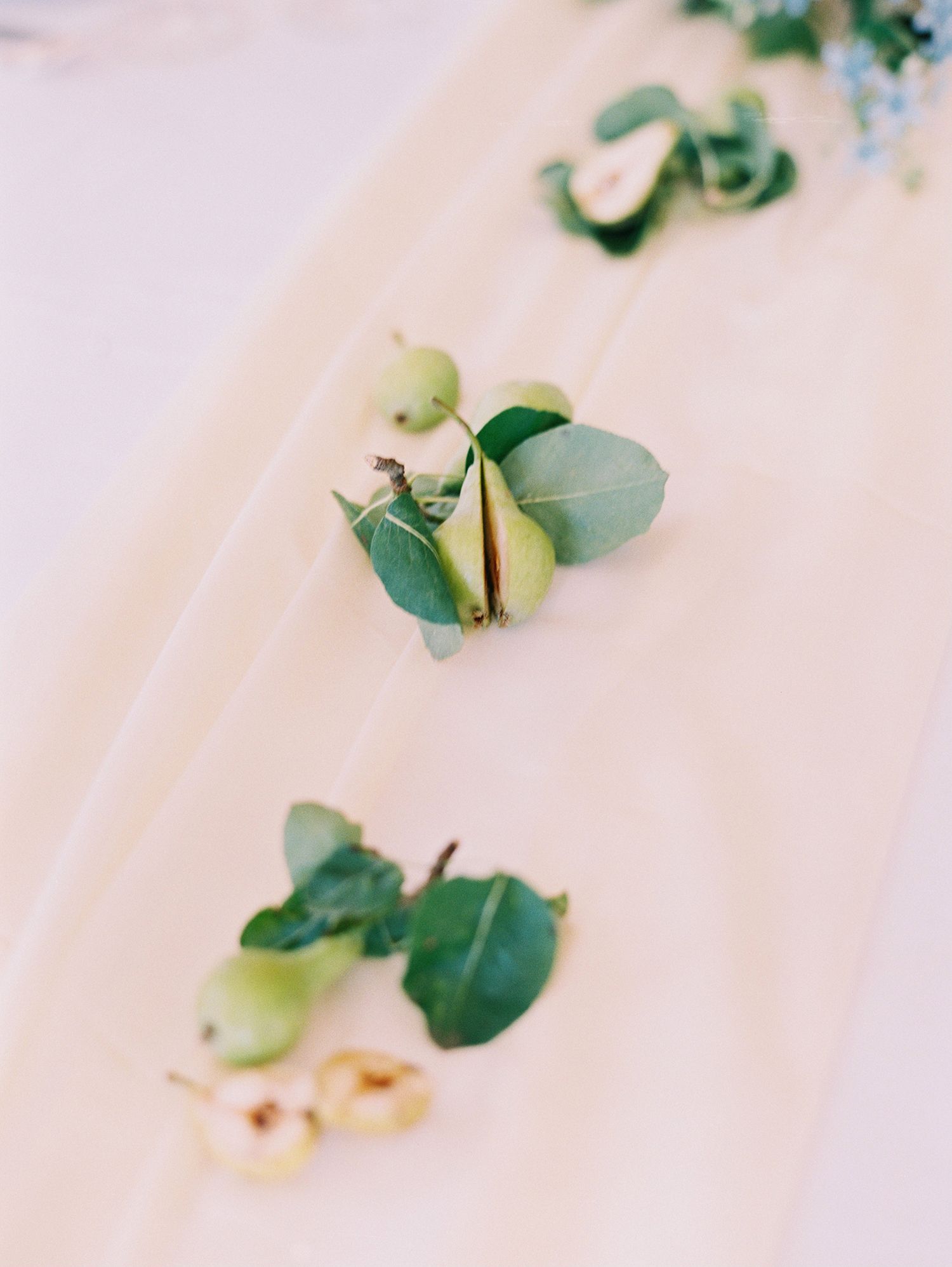 Fresh green eucalyptus leaves scattered on a light wooden surface.