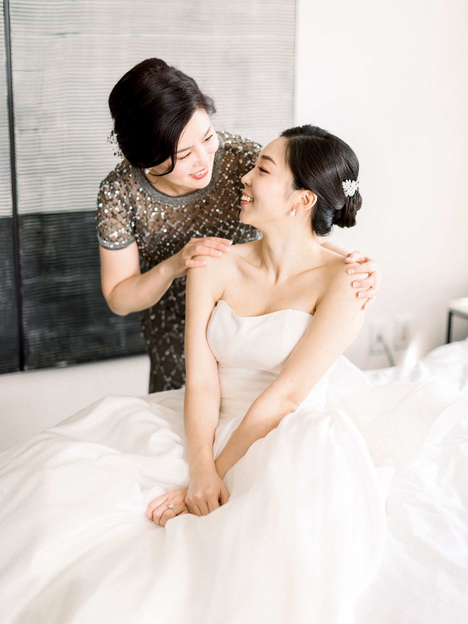 Intimate getting ready moments with bride in white gown being helped with final touches.