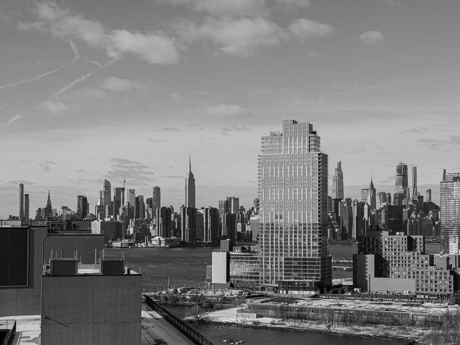 Black and white cityscape of New York City's iconic skyline with tall skyscrapers against a cloudy sky.