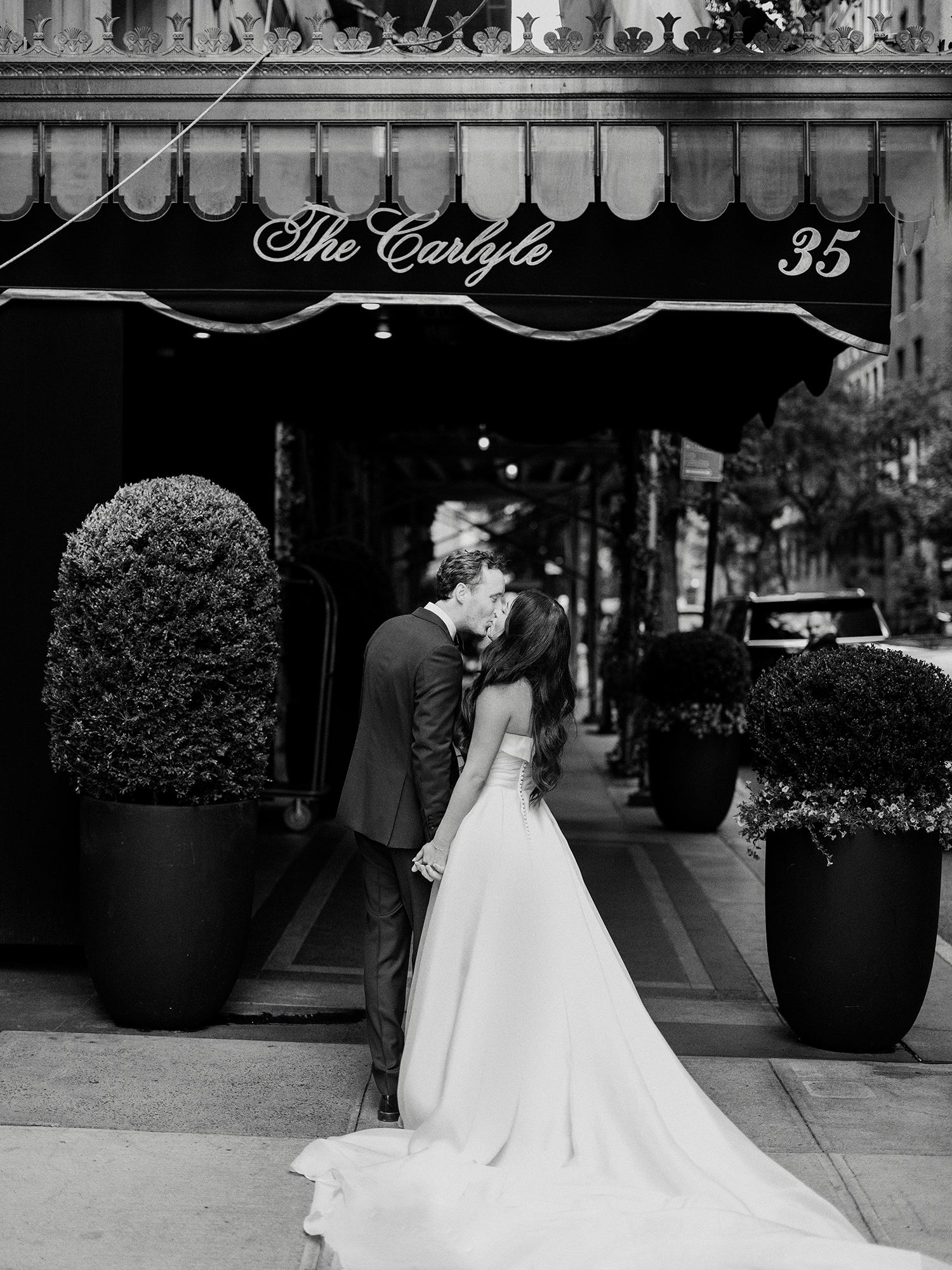 Black and white wedding photos taken outside The Carlyle hotel entrance with elegant planters. NYC wedding photographer.