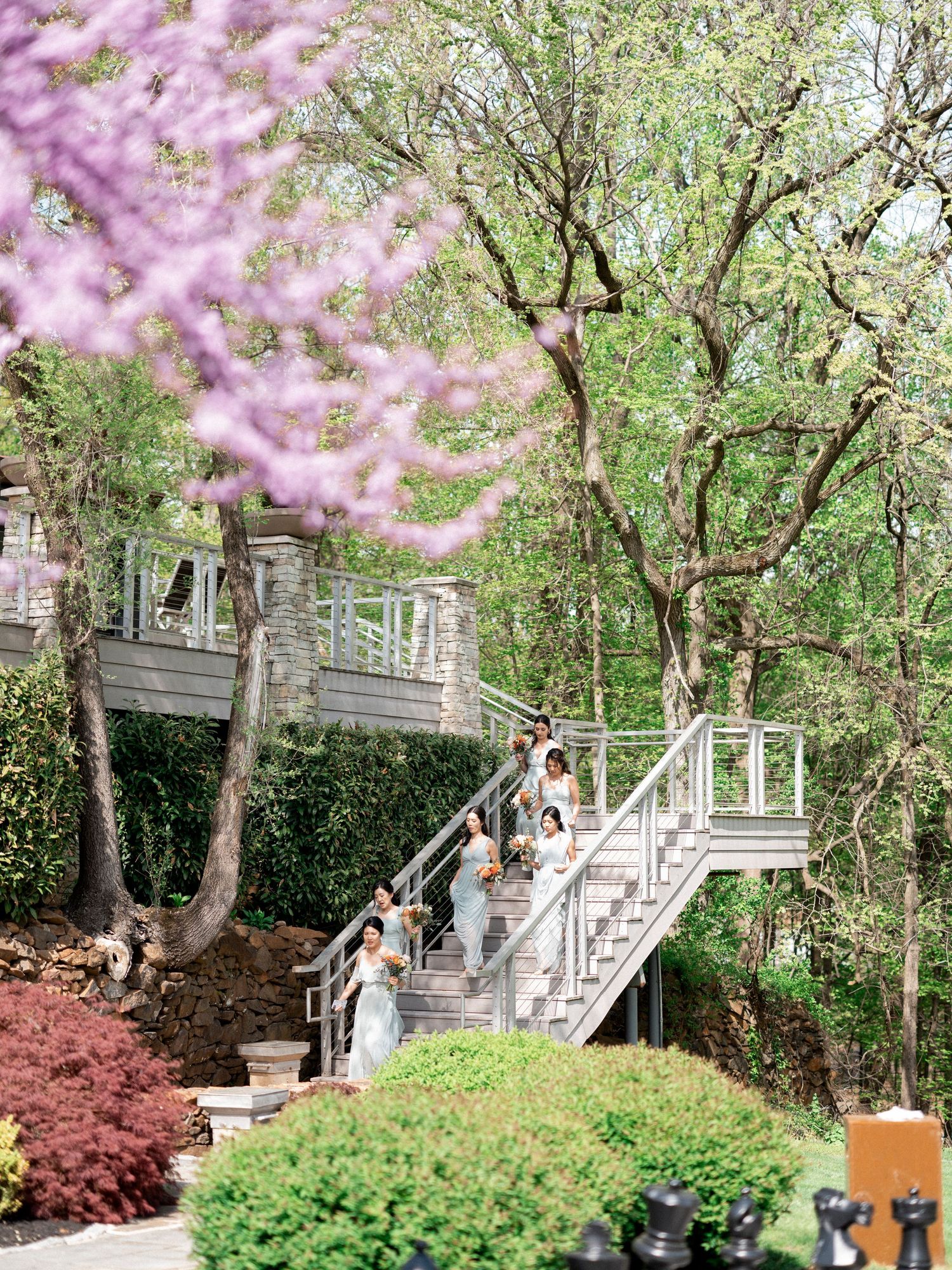 Wedding couple posing on stone steps surrounded by blooming cherry blossoms and spring greenery.