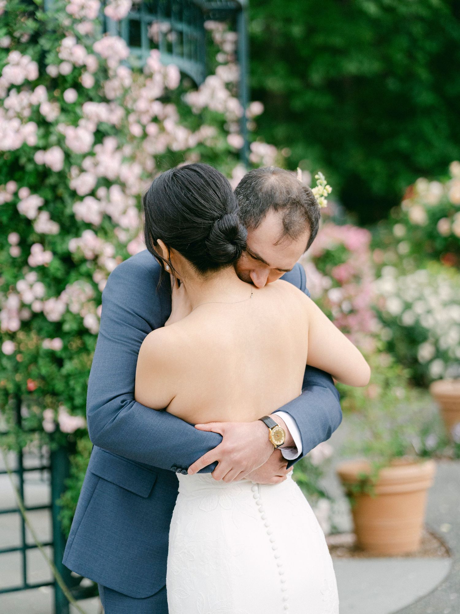 Intimate wedding couple moment captured among blooming pink garden roses.
