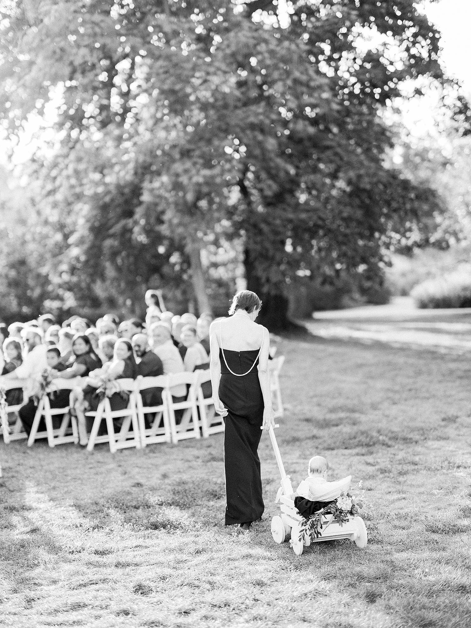 Outdoor wedding ceremony setup with white chairs arranged on a grassy lawn under trees. NYC wedding photographer.