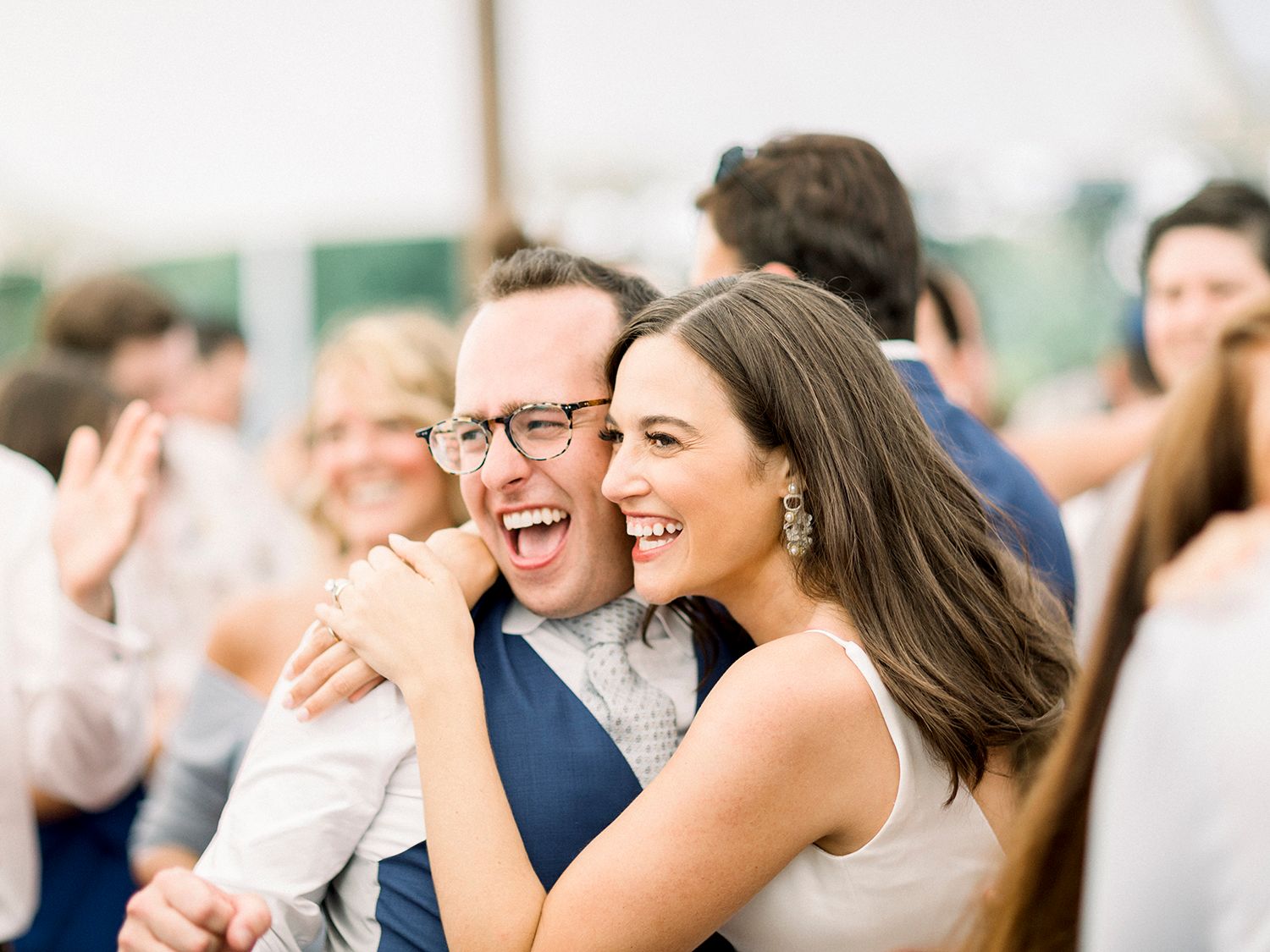 Wedding guests smile and cheer during a joyful reception celebration.