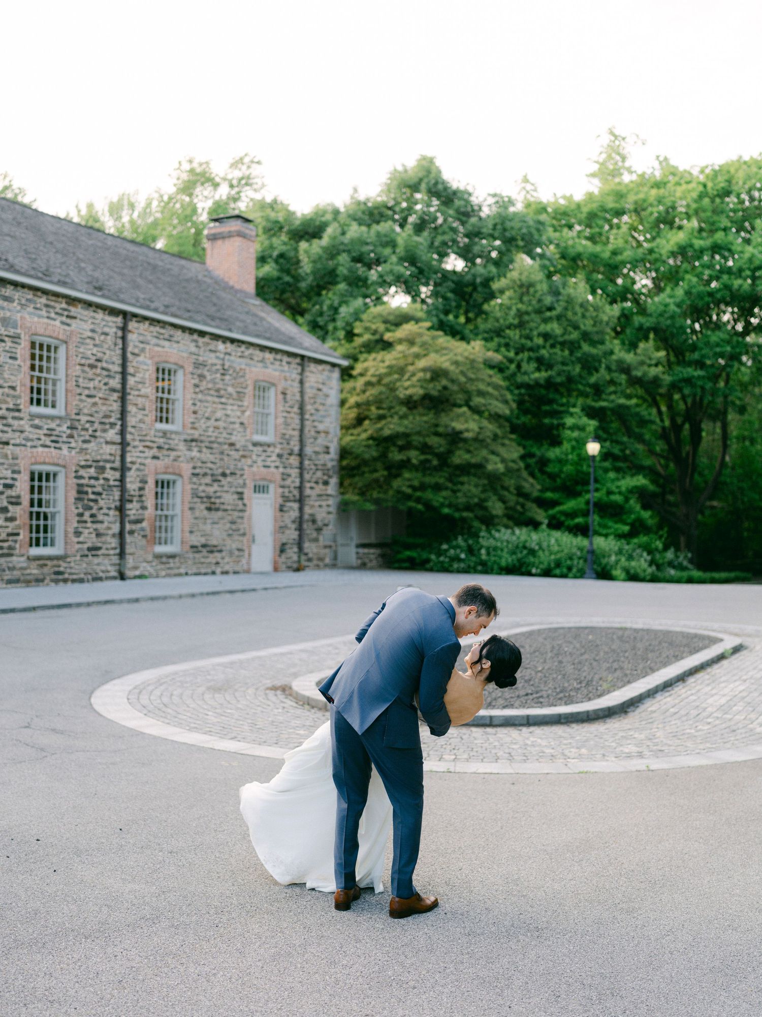 A romantic dip pose in front of a historic stone building.