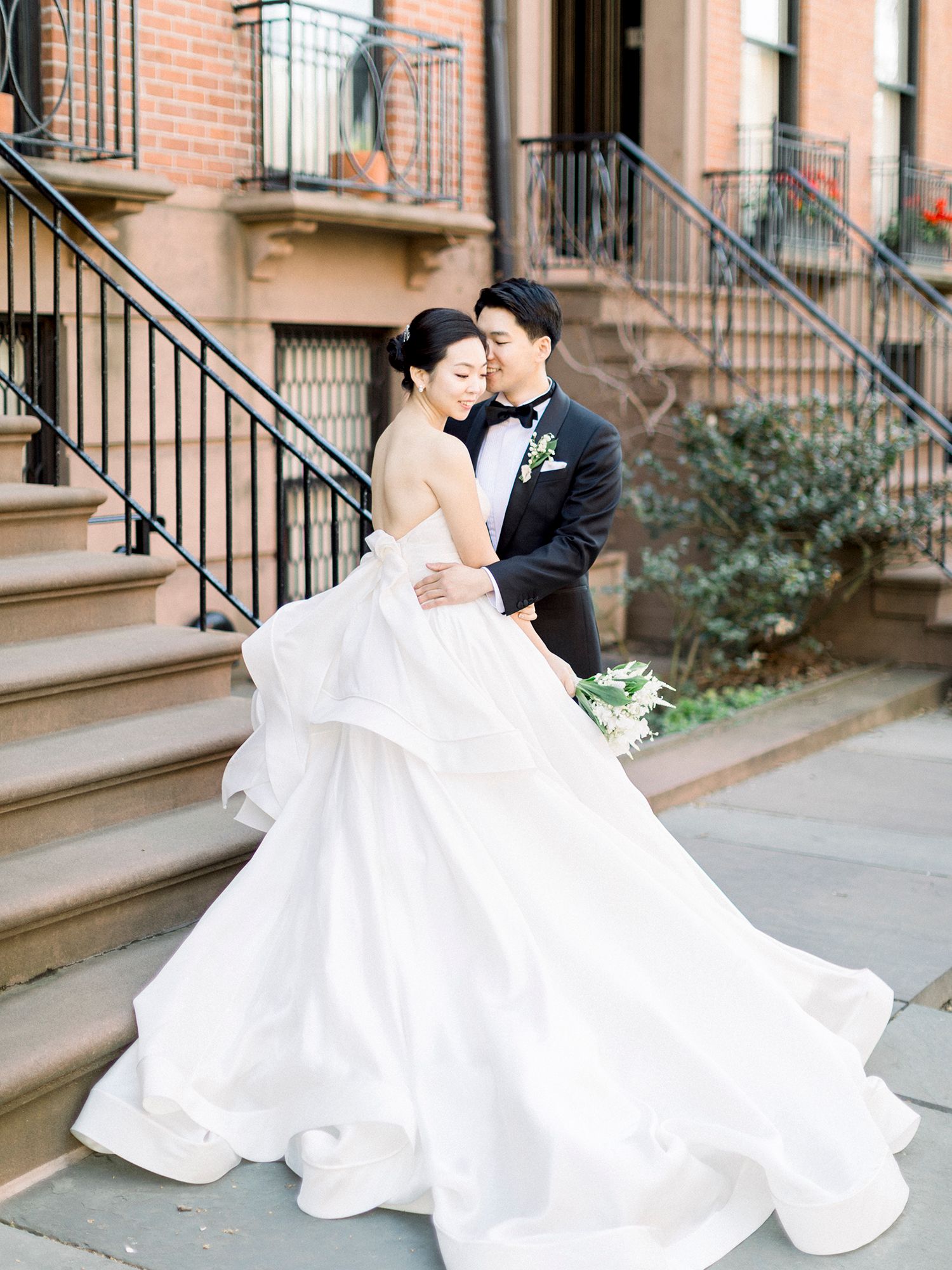 Romantic wedding couple embraces on historic brownstone steps. NYC wedding photographer.