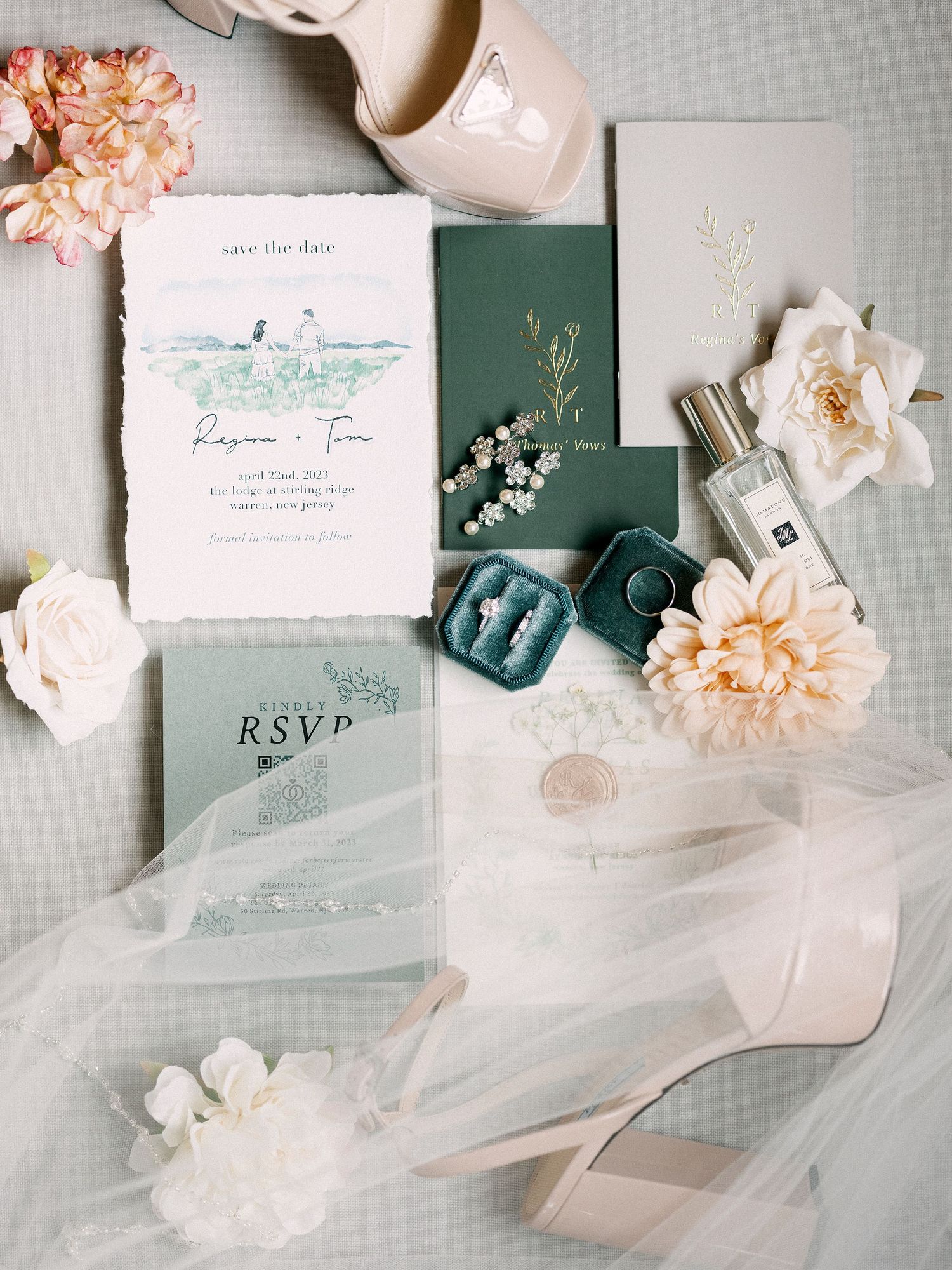 Wedding stationery flatlay with sage green invitations, blush flowers, and delicate white tulle details.