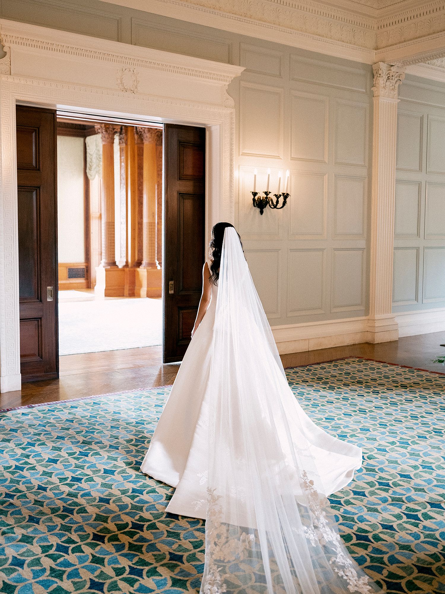 Wedding dress with flowing veil displayed in an elegant room with patterned floor. NYC wedding photographer.