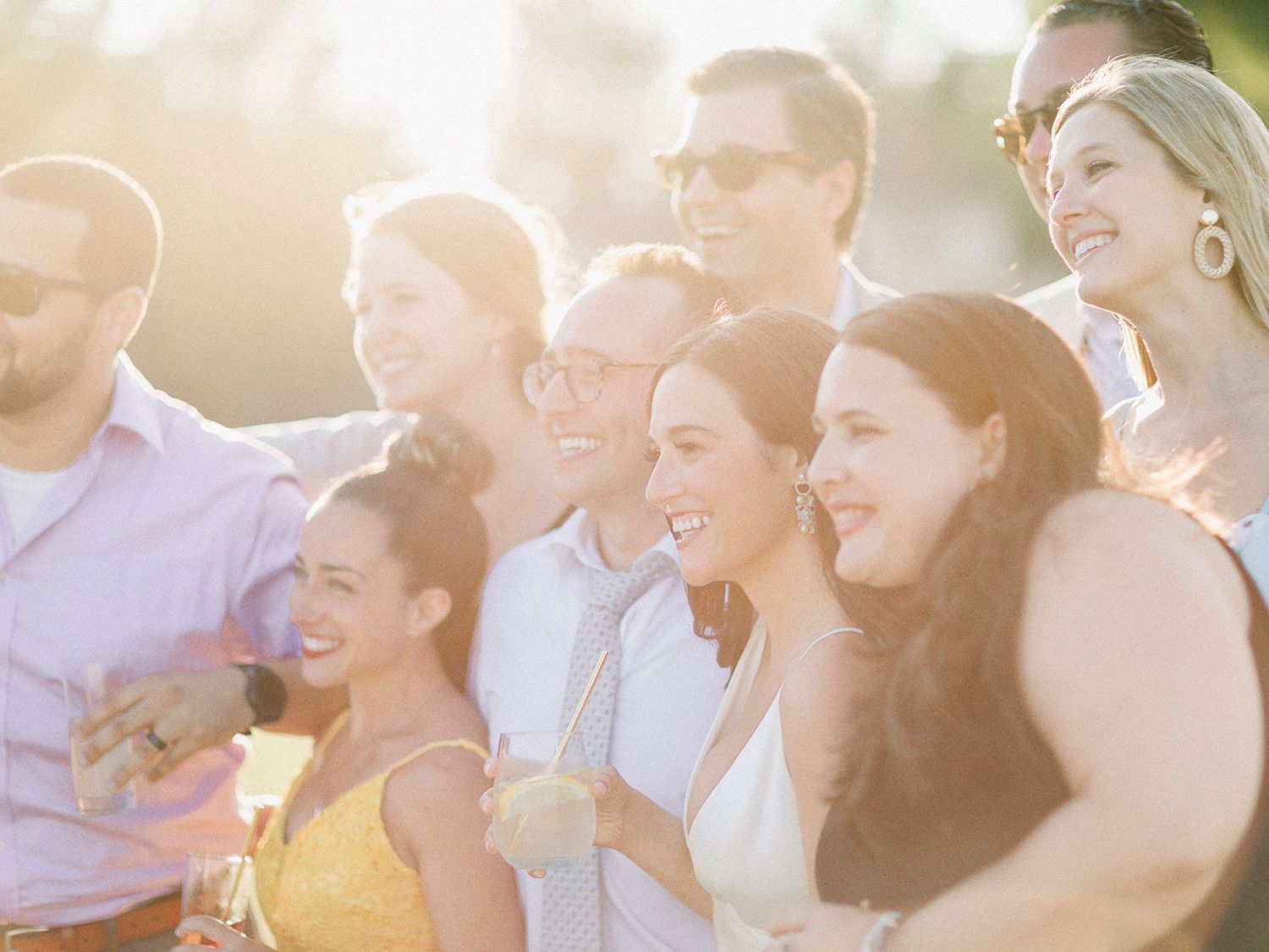 Wedding guests smile and laugh during an outdoor reception celebration.
