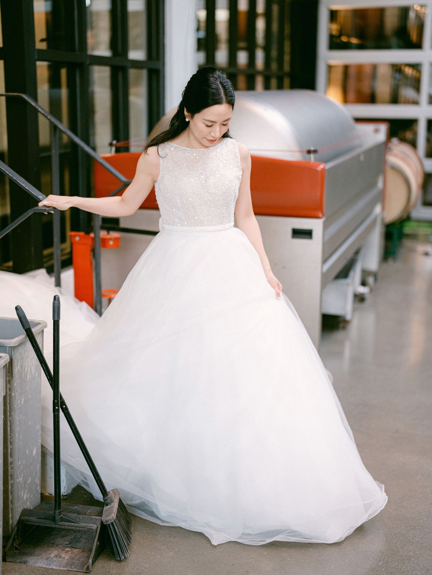 Wedding dress detail shot showing flowing white ballgown skirt in industrial setting.