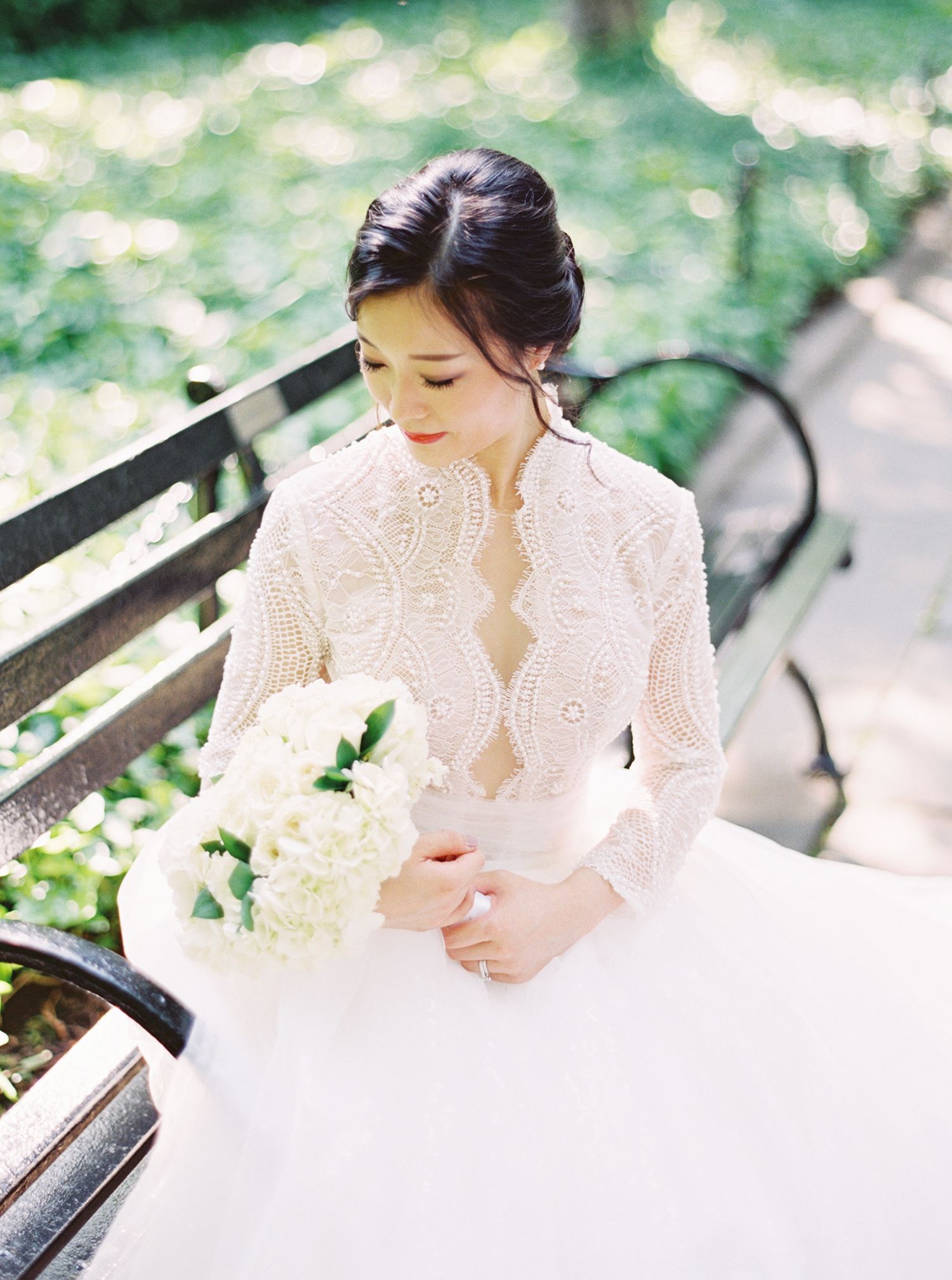 Delicate lace details of a white wedding dress captured in soft natural lighting outdoors. NYC wedding photographer.