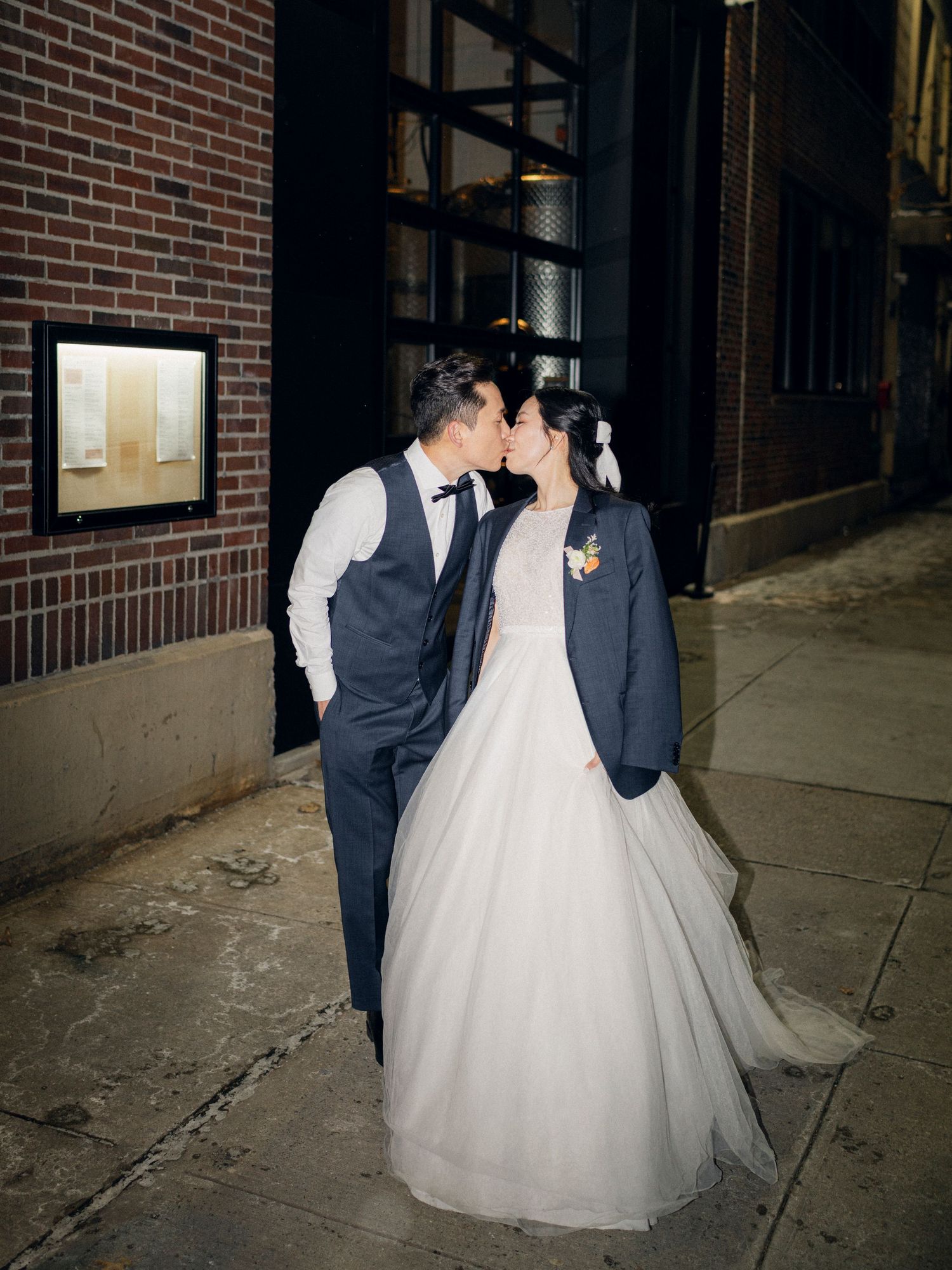 A tender wedding moment against a brick wall backdrop in an urban setting.