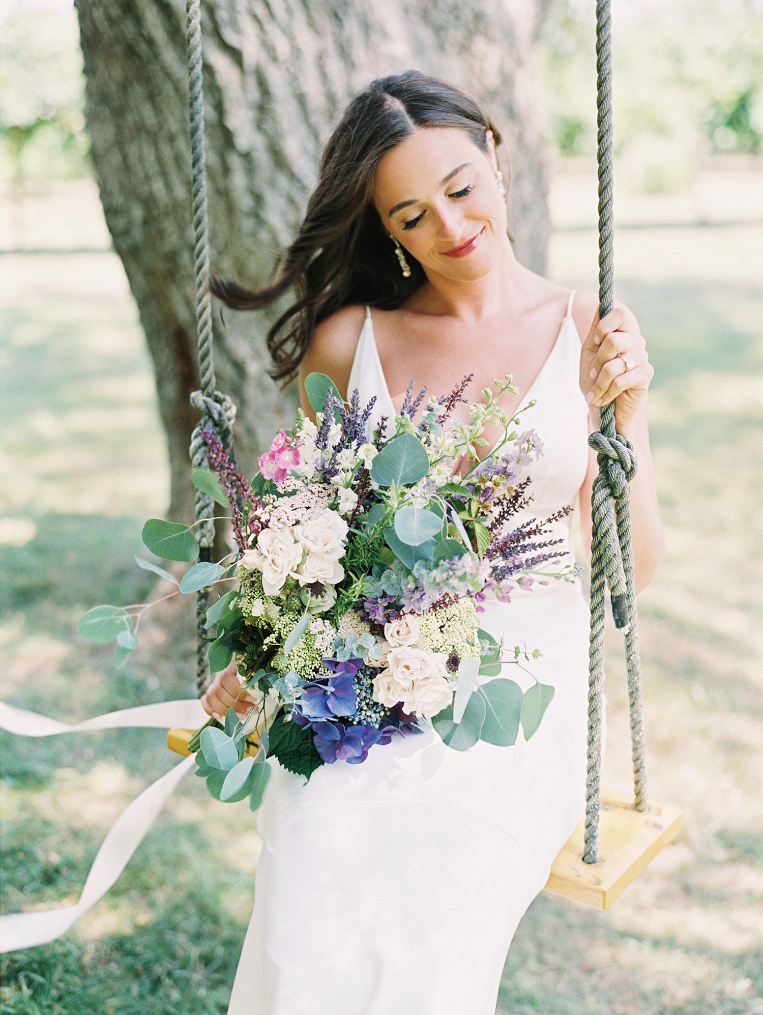 Dreamy wedding photos featuring a tree swing decorated with delicate flowers and greenery. NYC wedding photographer.