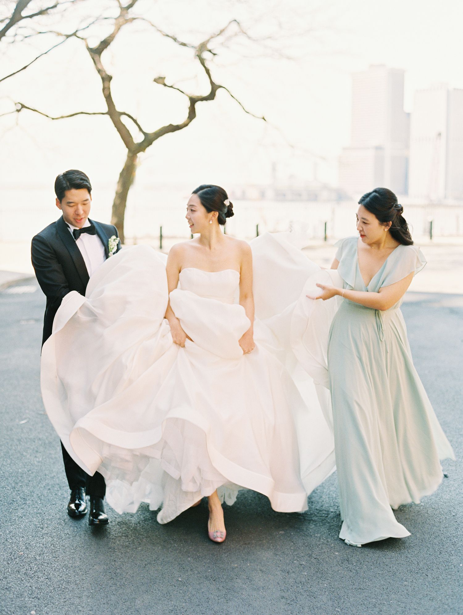 Wedding party in soft pastels walks together against urban backdrop.