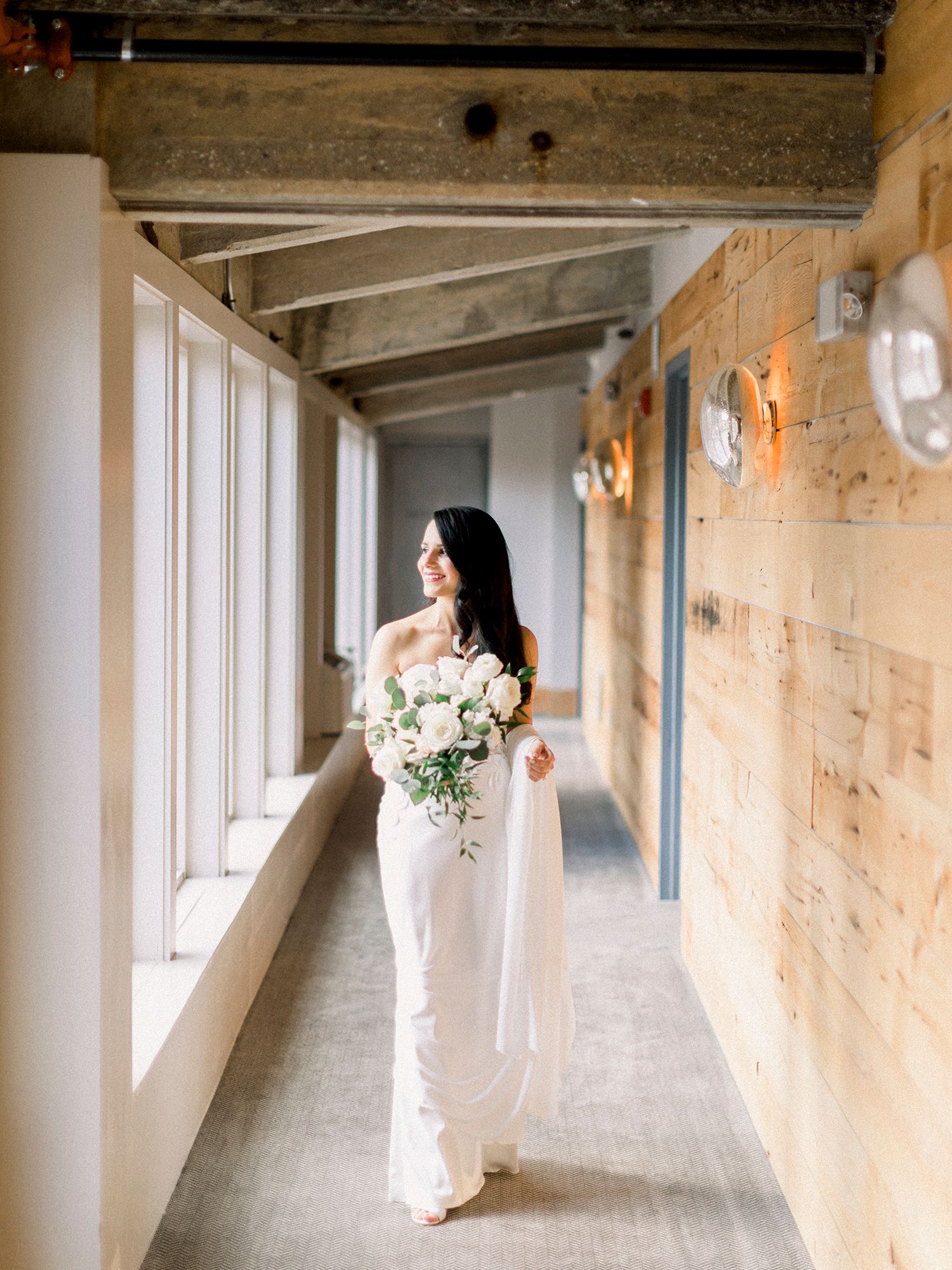 Elegant bridal photos in a rustic stone hallway with natural window light.