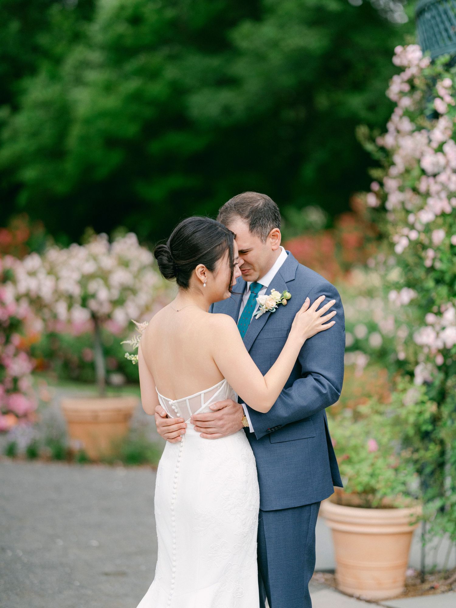 Romantic garden wedding portraits with couple surrounded by climbing pink roses.