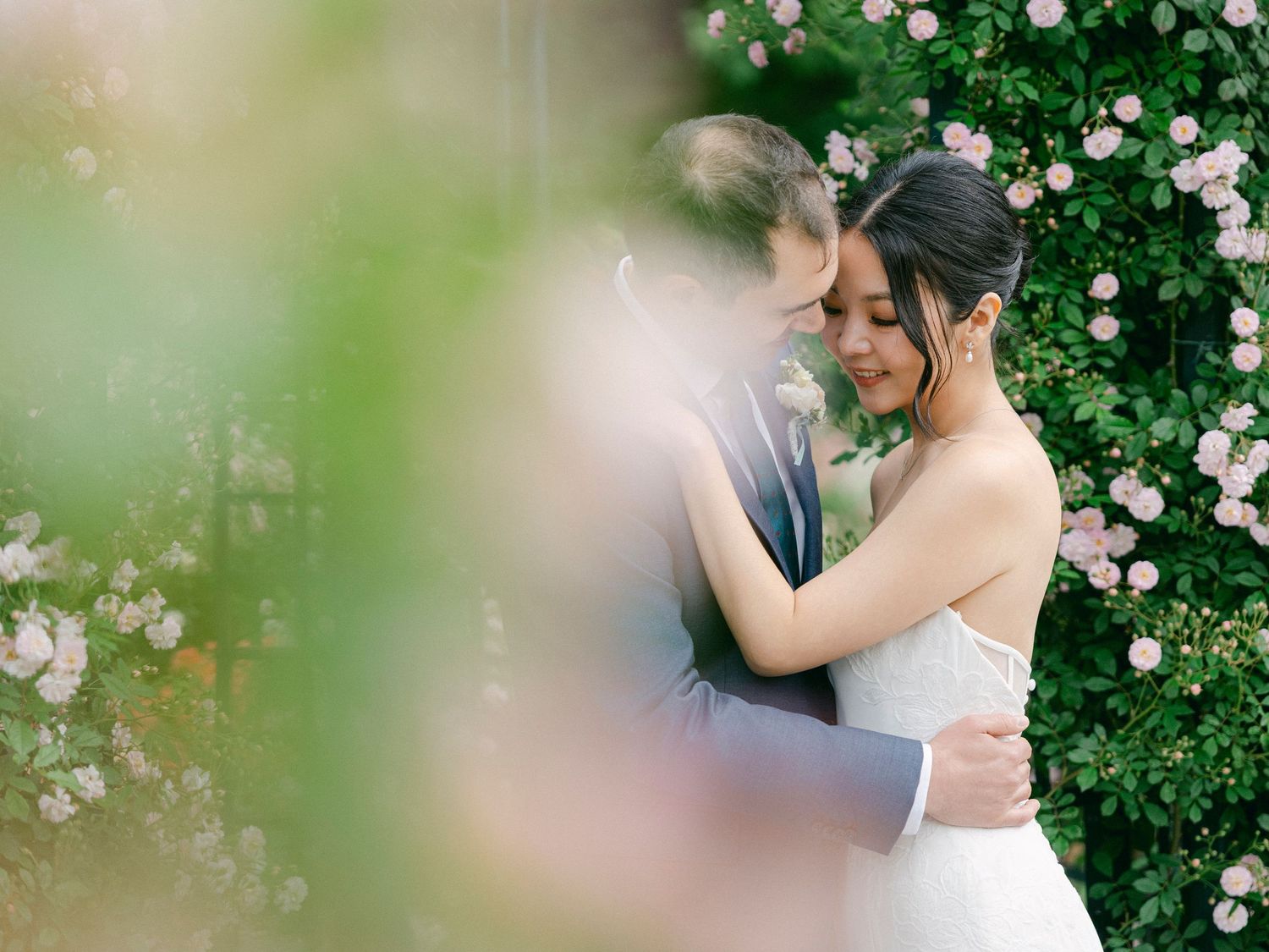 Soft focus wedding photography through flowering branches in garden setting.