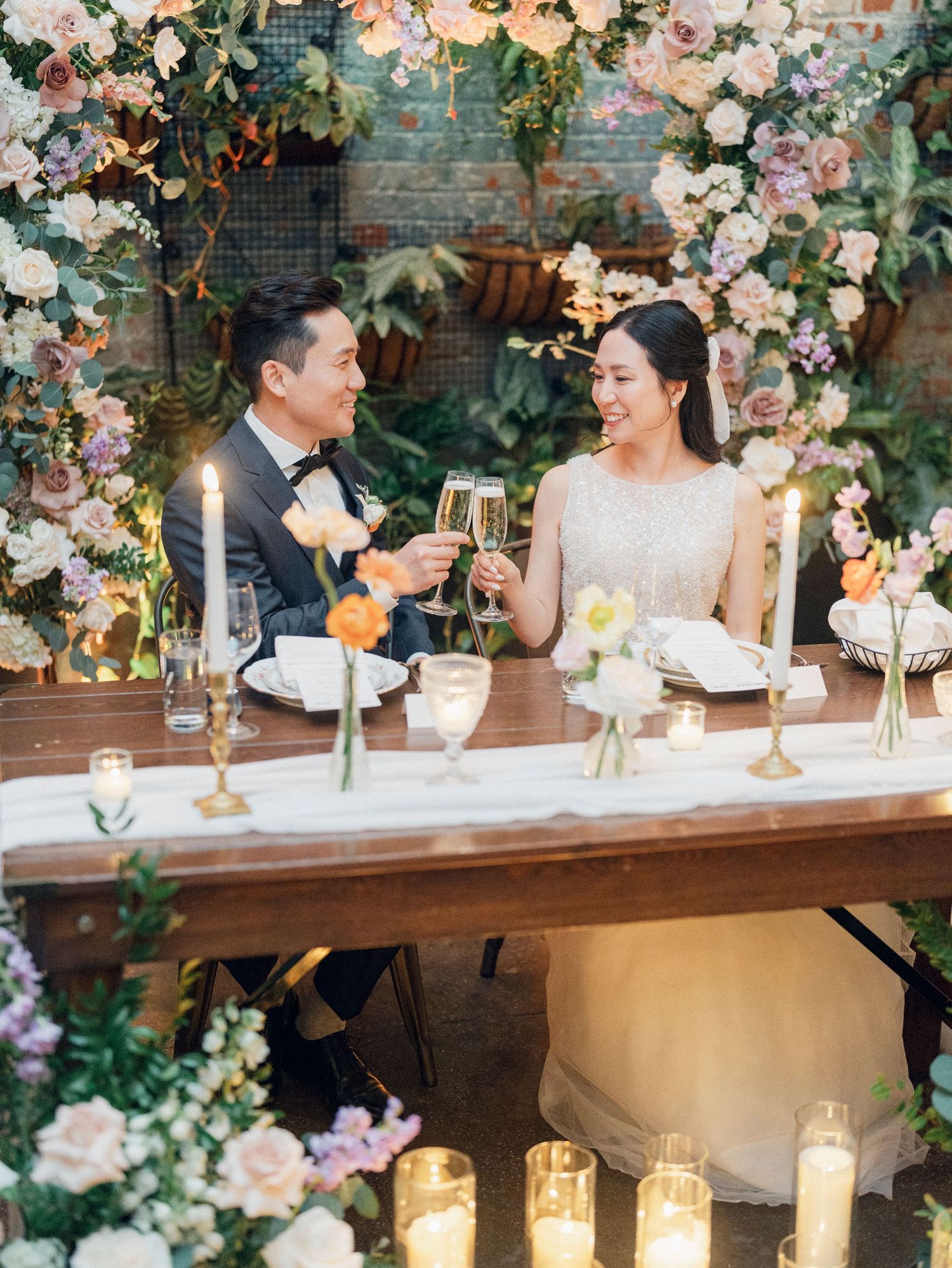 Elegant wedding reception table decorated with blush and white floral arrangements and candlelight.