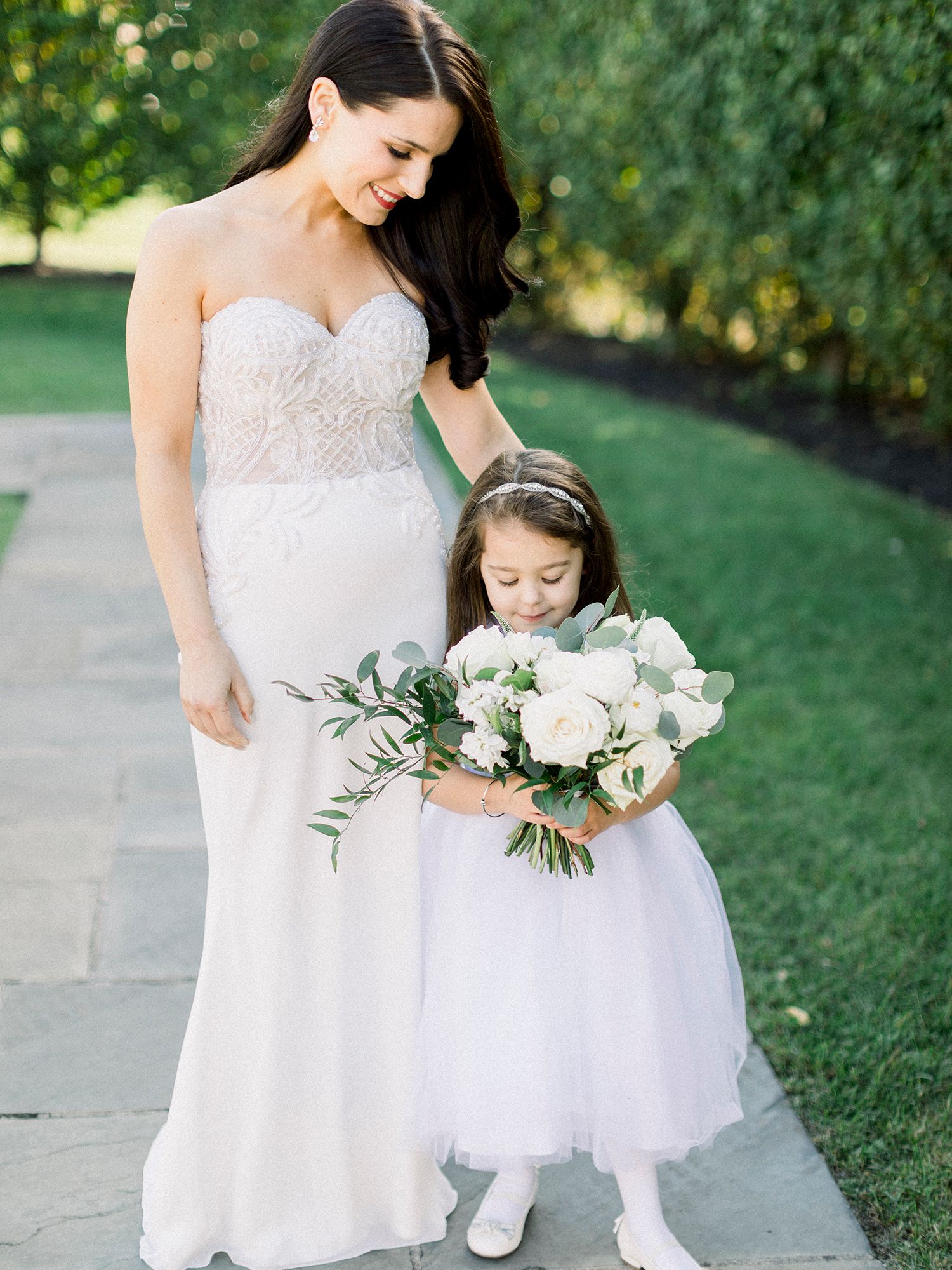 Sweet moment between bride in white gown and young flower girls holding bouquets.