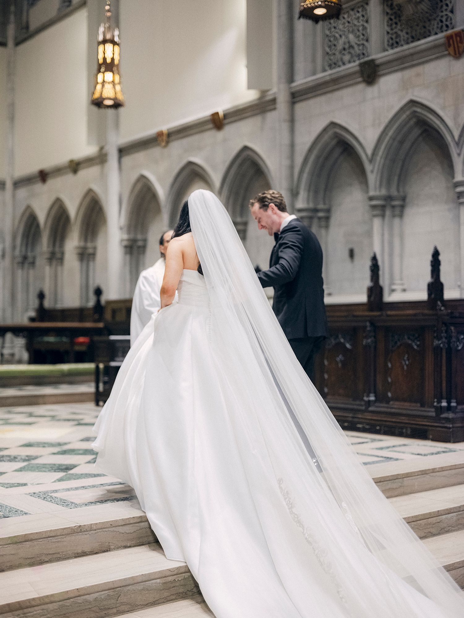 Wedding couple photographed in a grand cathedral with gothic arches and ornate architectural details. NYC wedding photographer.