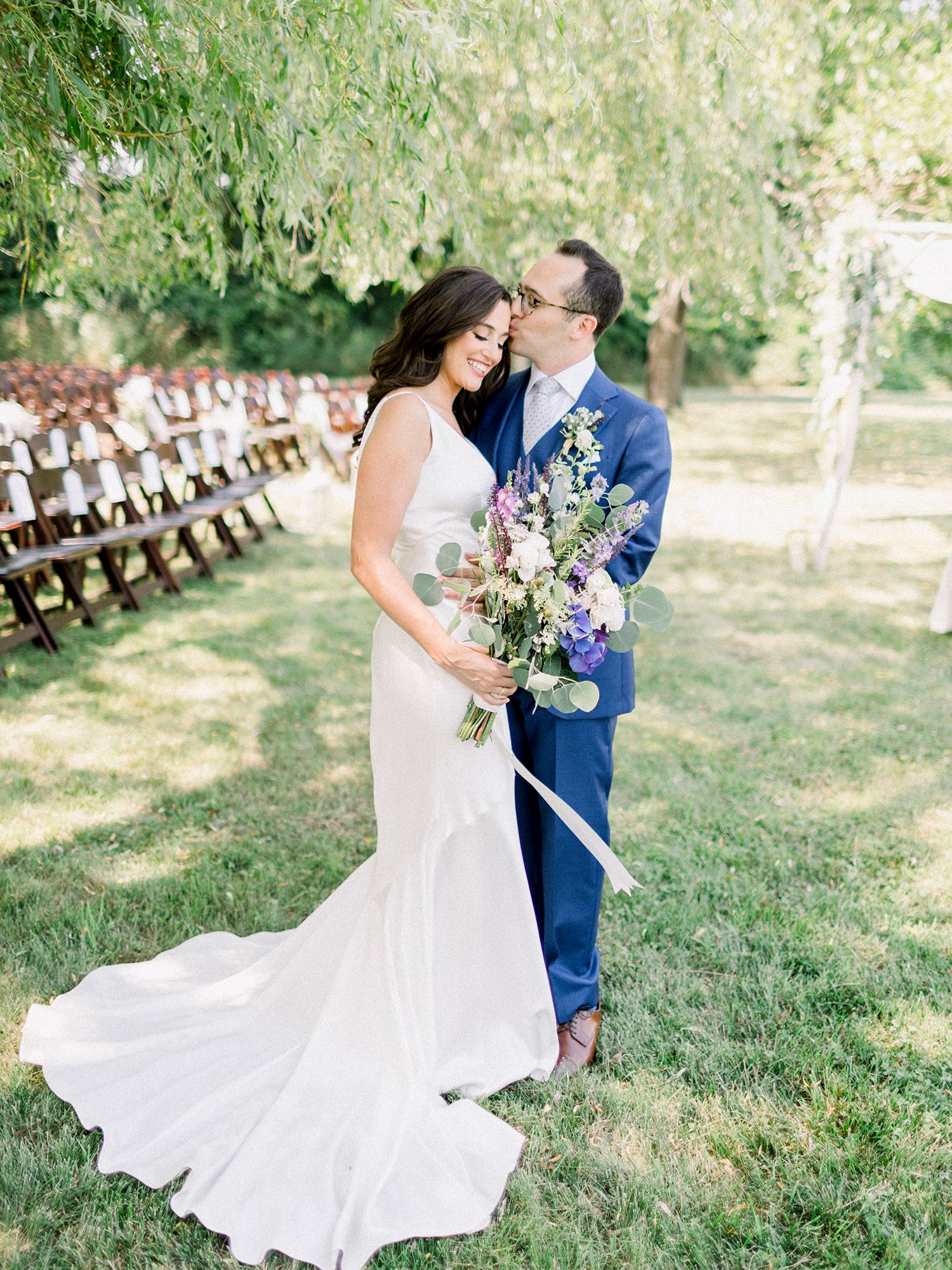 Romantic wedding couple dancing in a garden setting with white dress flowing in the breeze.
