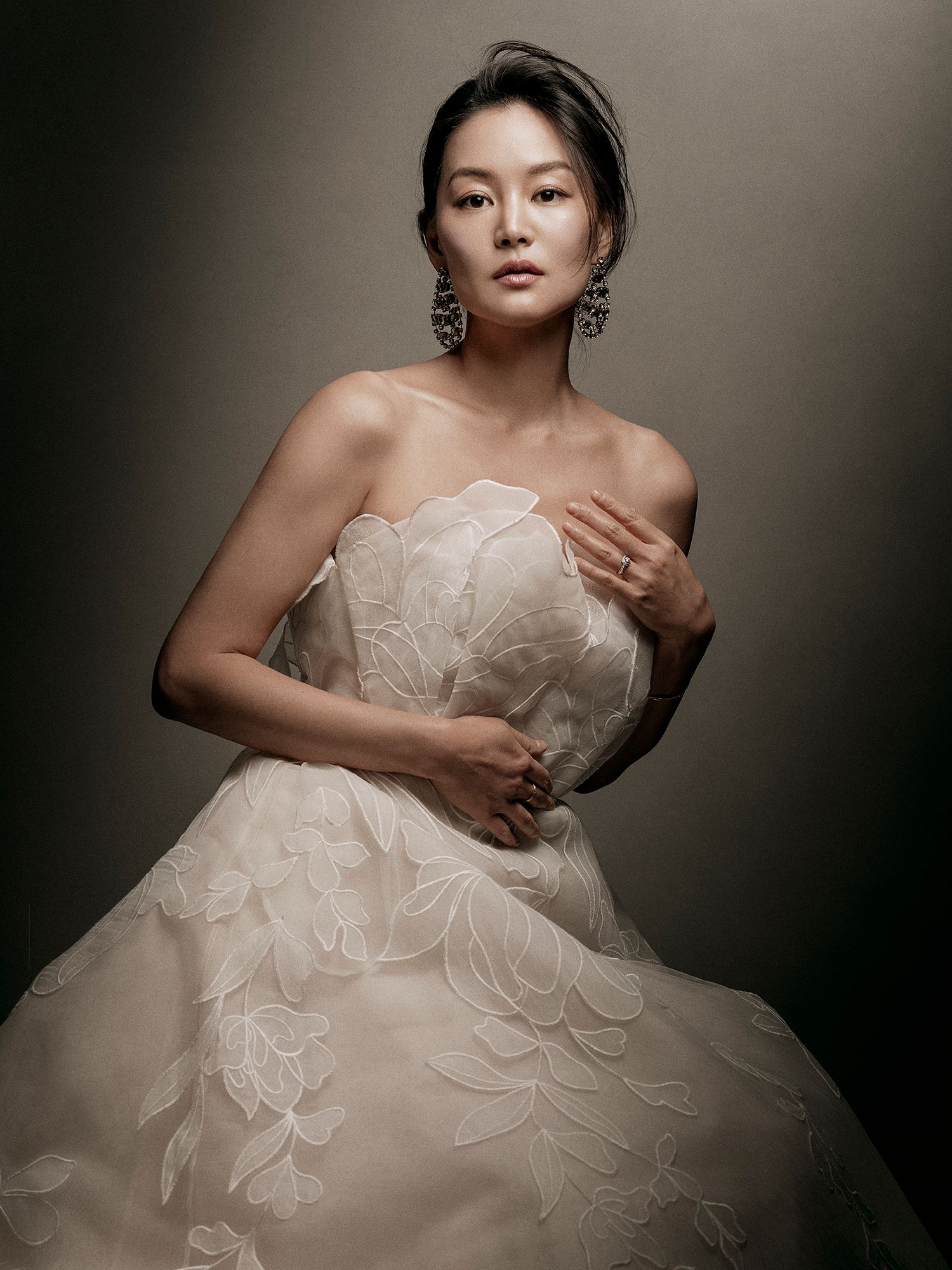 Artistic bridal portrait series showing elegant white wedding gown with ruffled details against dark dramatic backdrop.