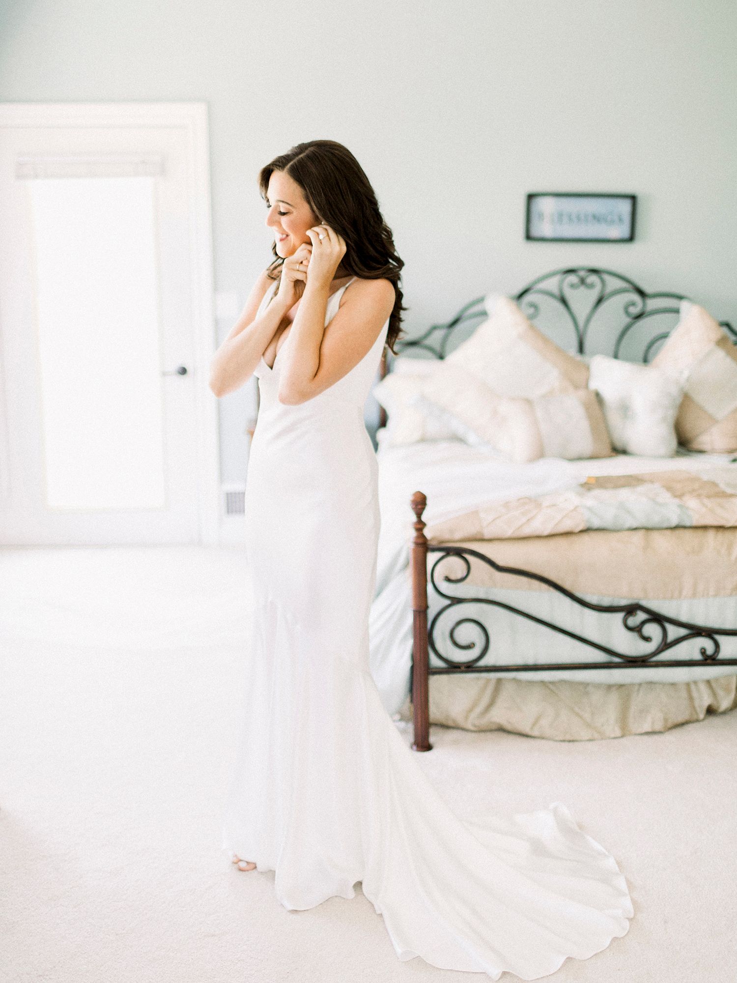 Woman in white dress sitting on an ornate bed during an emotional moment.