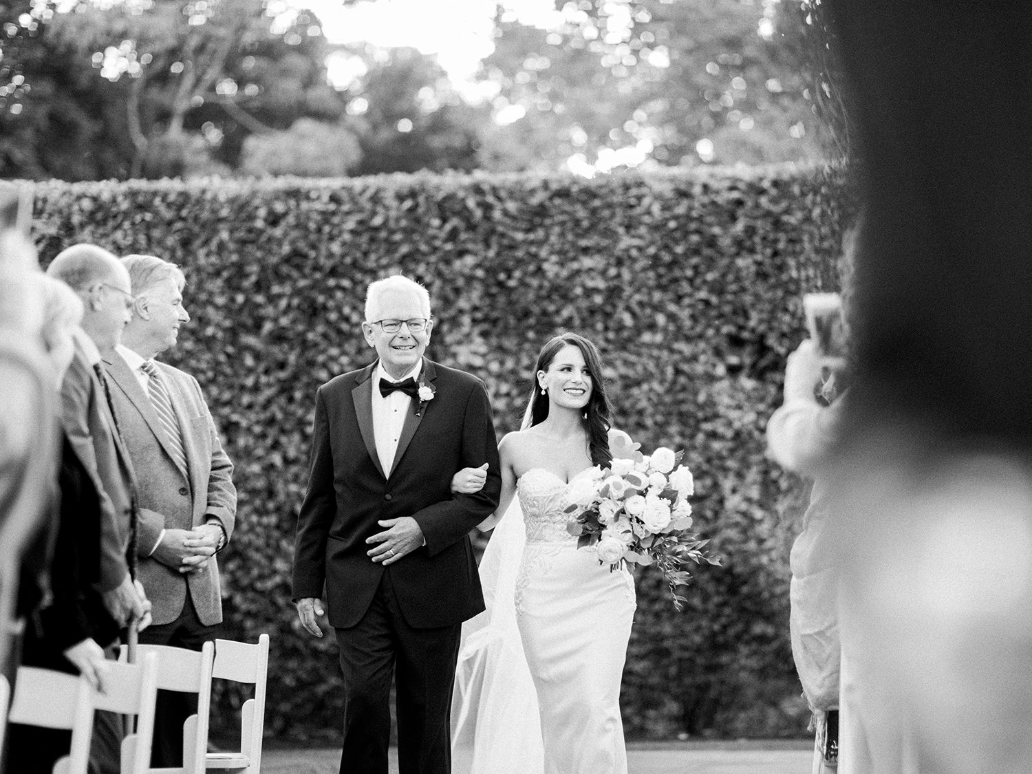 Black and white photo of wedding guests mingling during an outdoor garden reception.