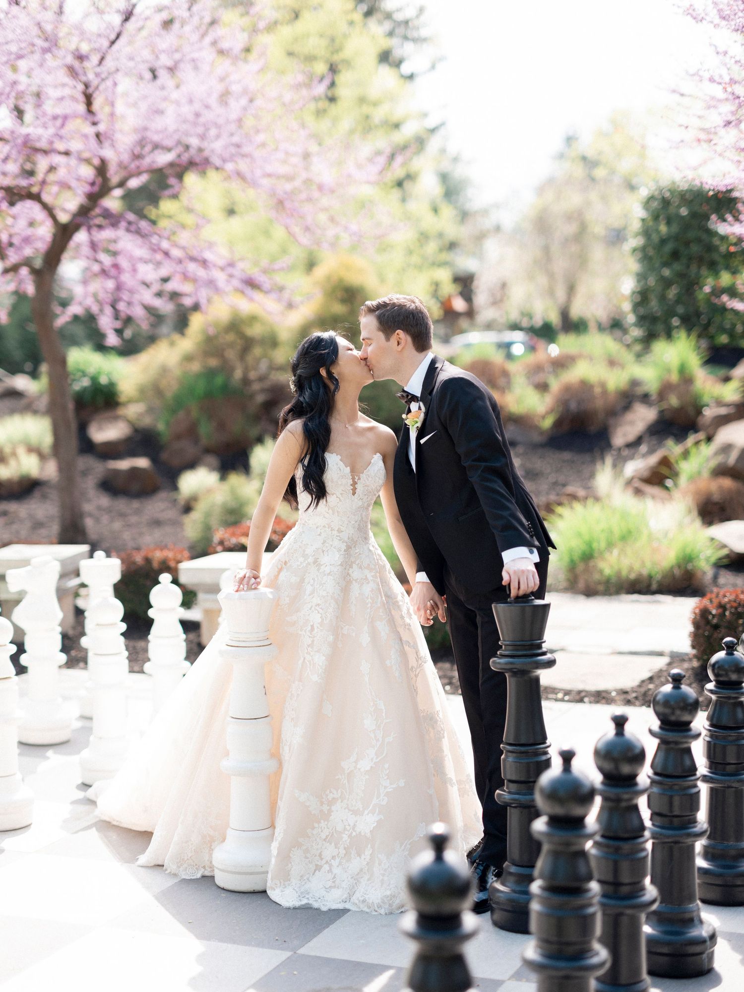 Elegant wedding photos incorporating oversized chess pieces and spring blossoms as creative props.
