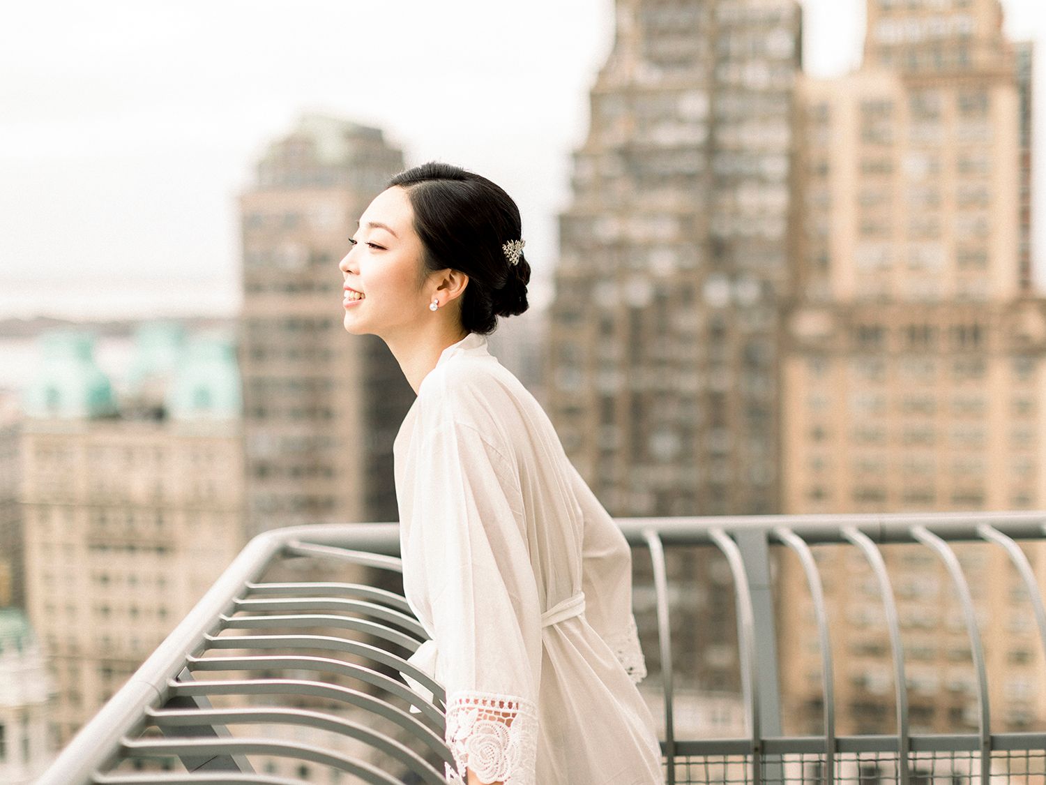 Urban rooftop scene with railing and city buildings in soft daylight.