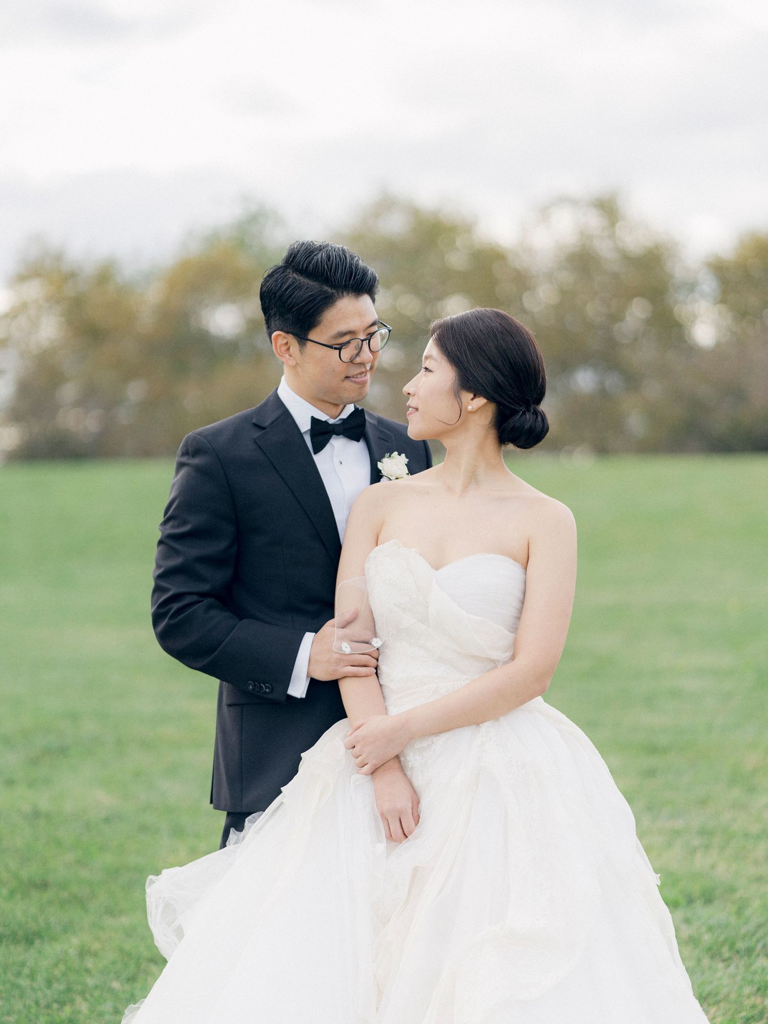 Couple shares tender moments while posing in a grassy field on their wedding day.