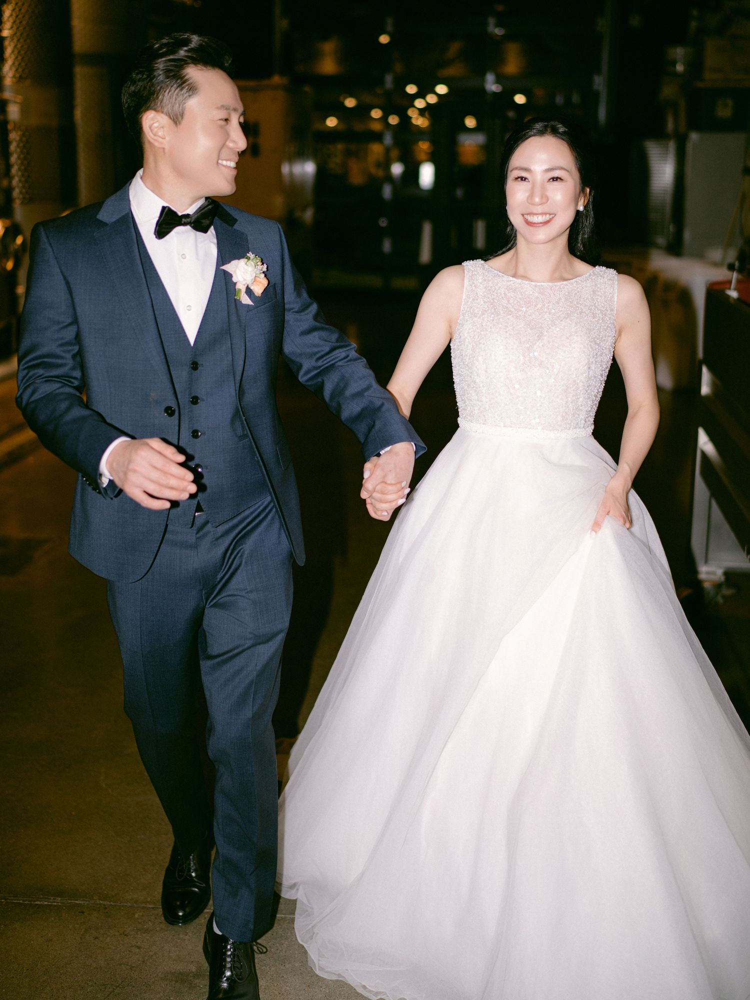 Wedding couple dancing and laughing in an elegantly lit venue.