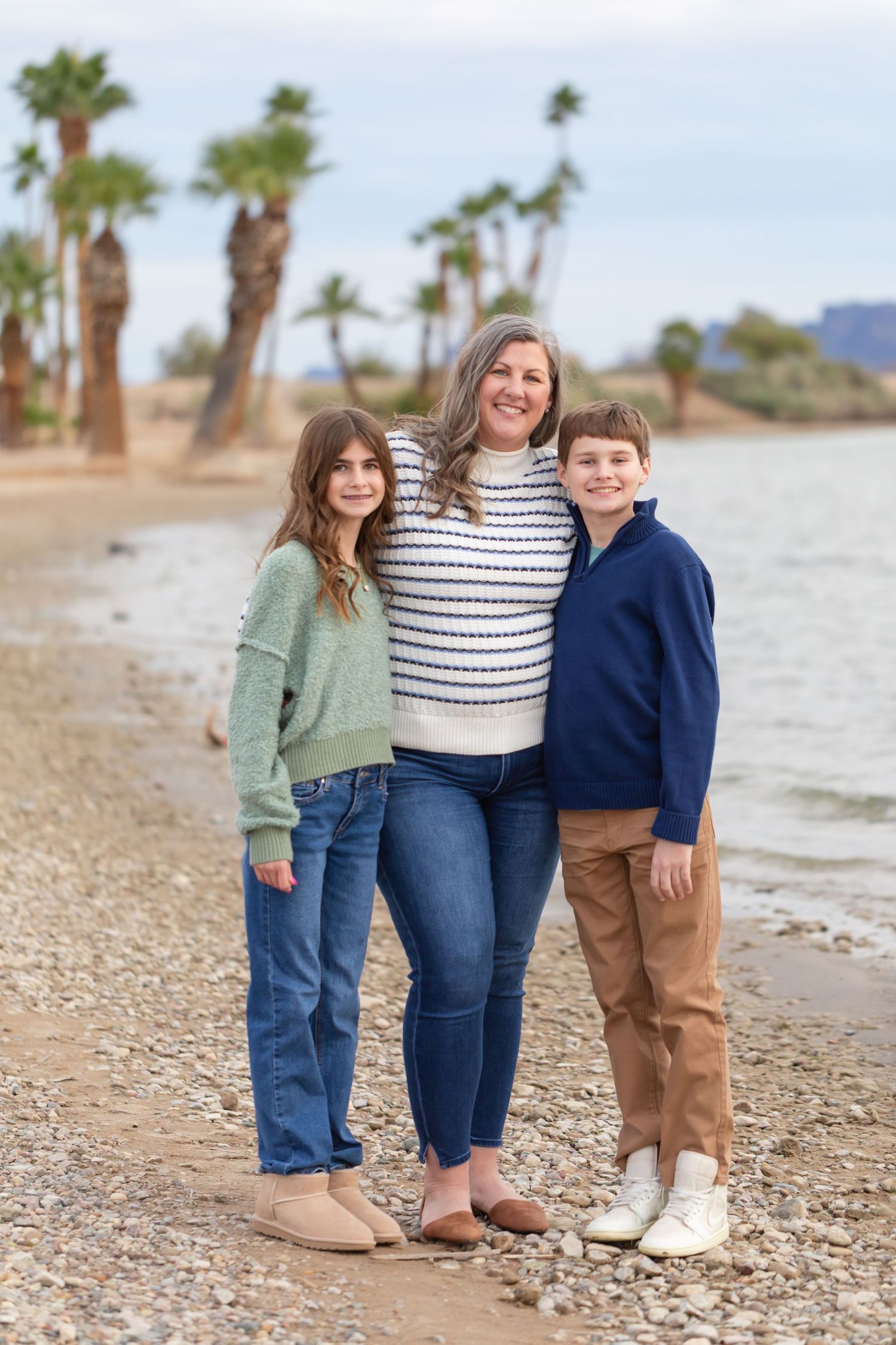 Family group poses together on rocky rotary park beach in lake havasu city az with palm trees in background at rotary park beach lake havasu