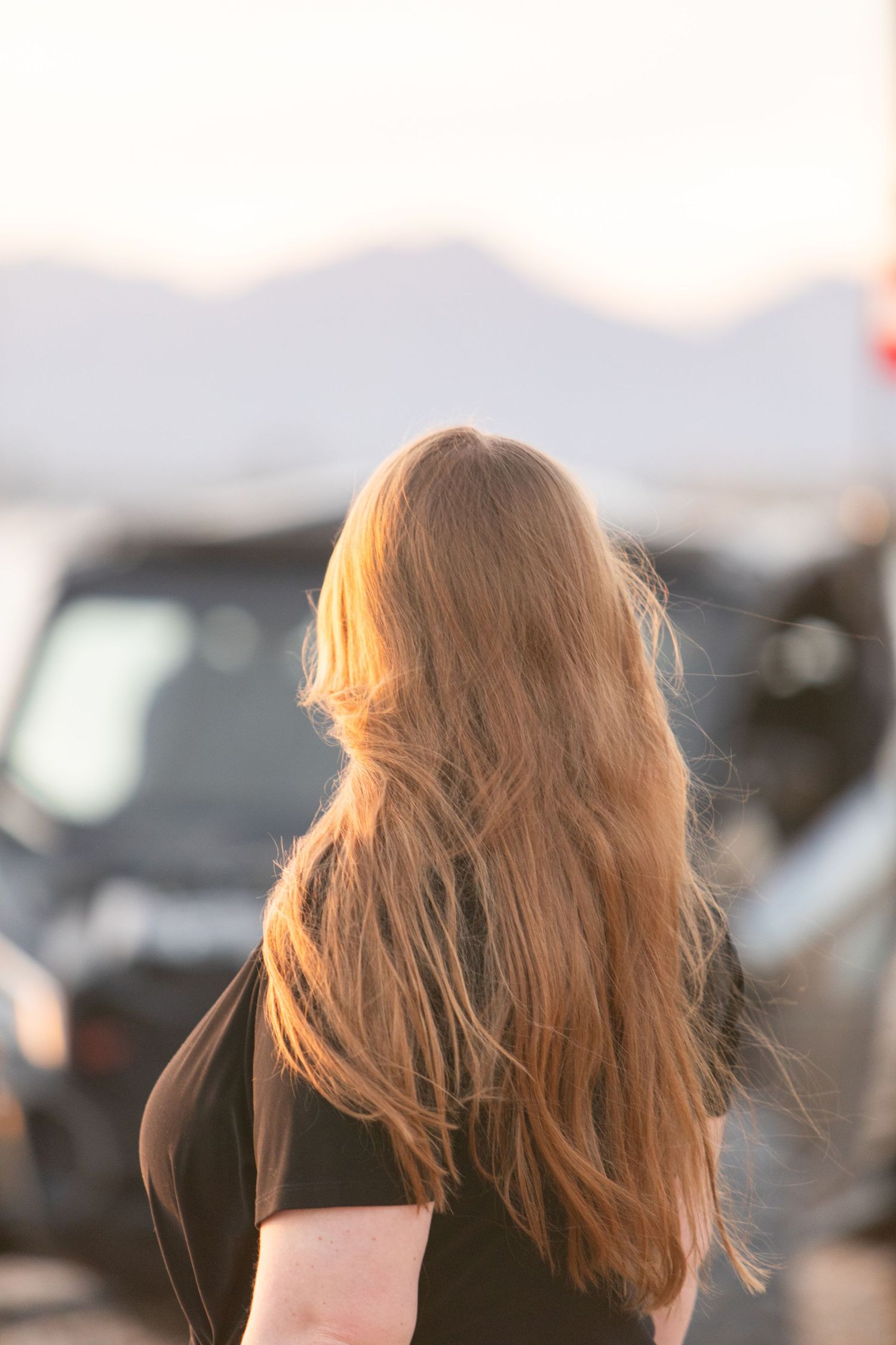 Backlit portrait of long blonde hair blowing in wind at sunset.