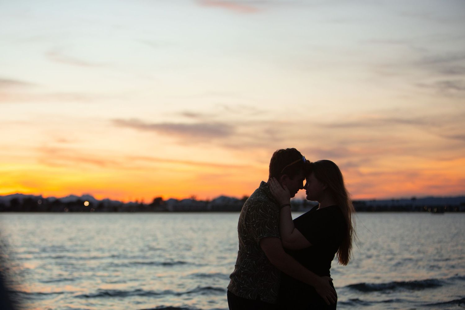 Silhouette of a couple embracing against a colorful sunset sky over lake havasu