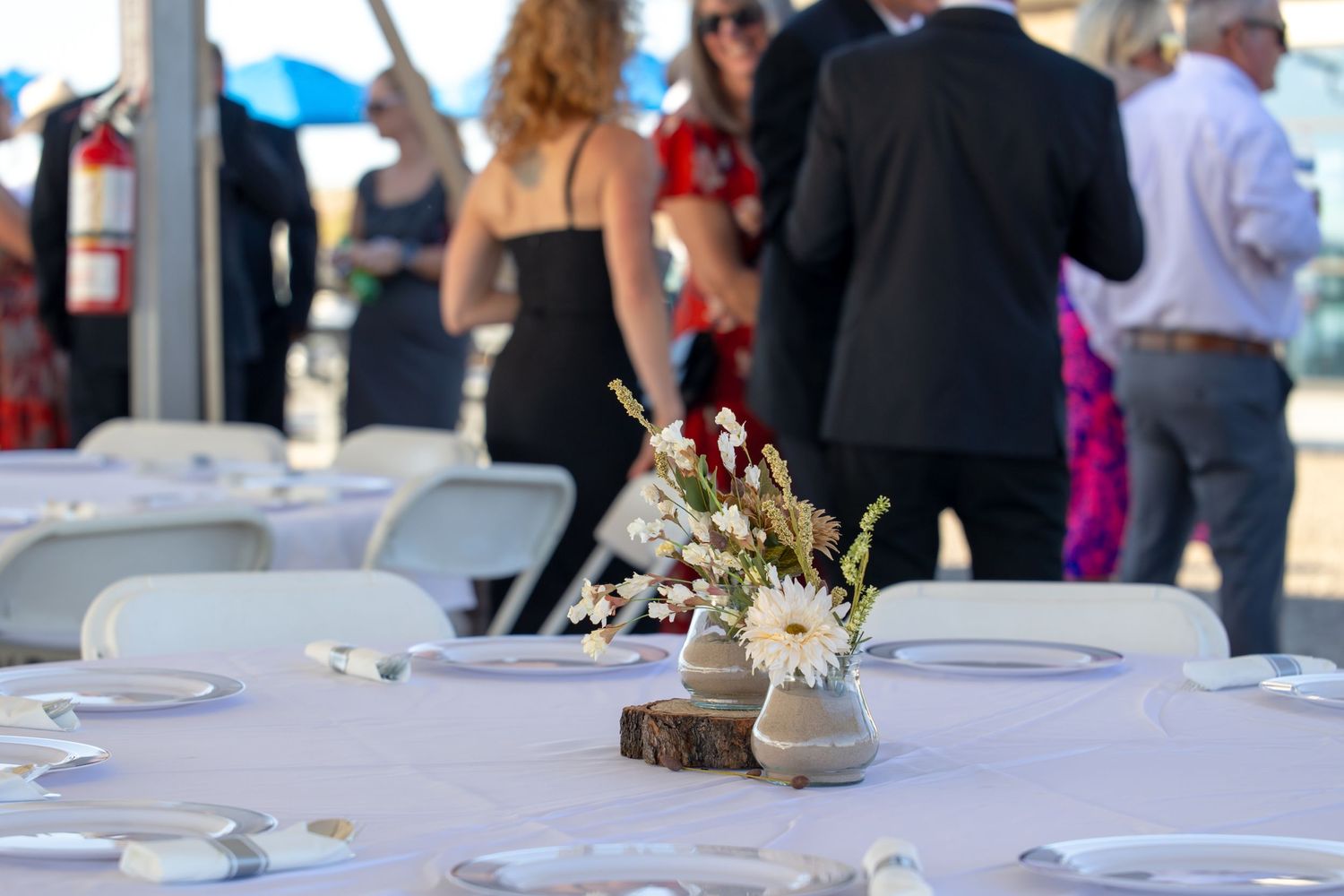 Rustic wedding table setting with wood slice centerpiece and floral arrangement on white tablecloth at outdoor reception in Lake Havasu City