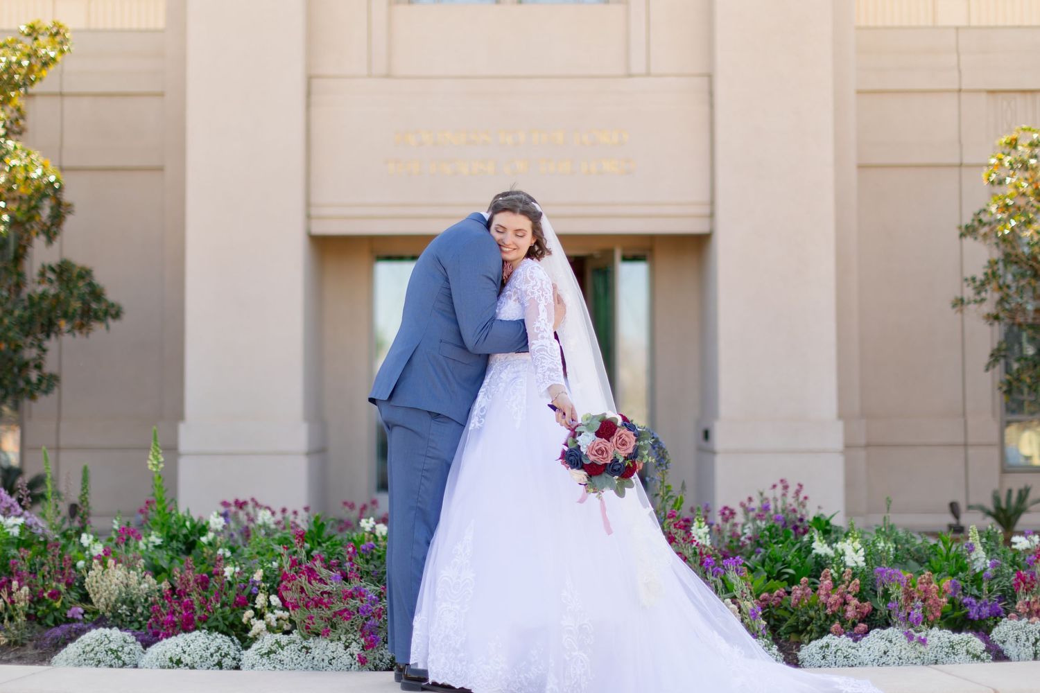 Elegant wedding portraits taken against architectural columns with purple flowers.