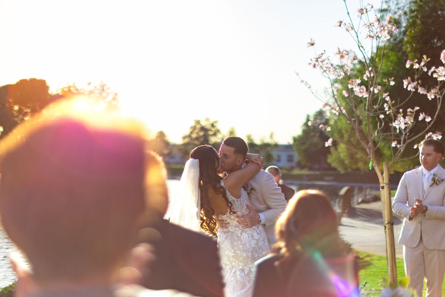 Wedding celebration silhouettes against golden sunset with lens flare.