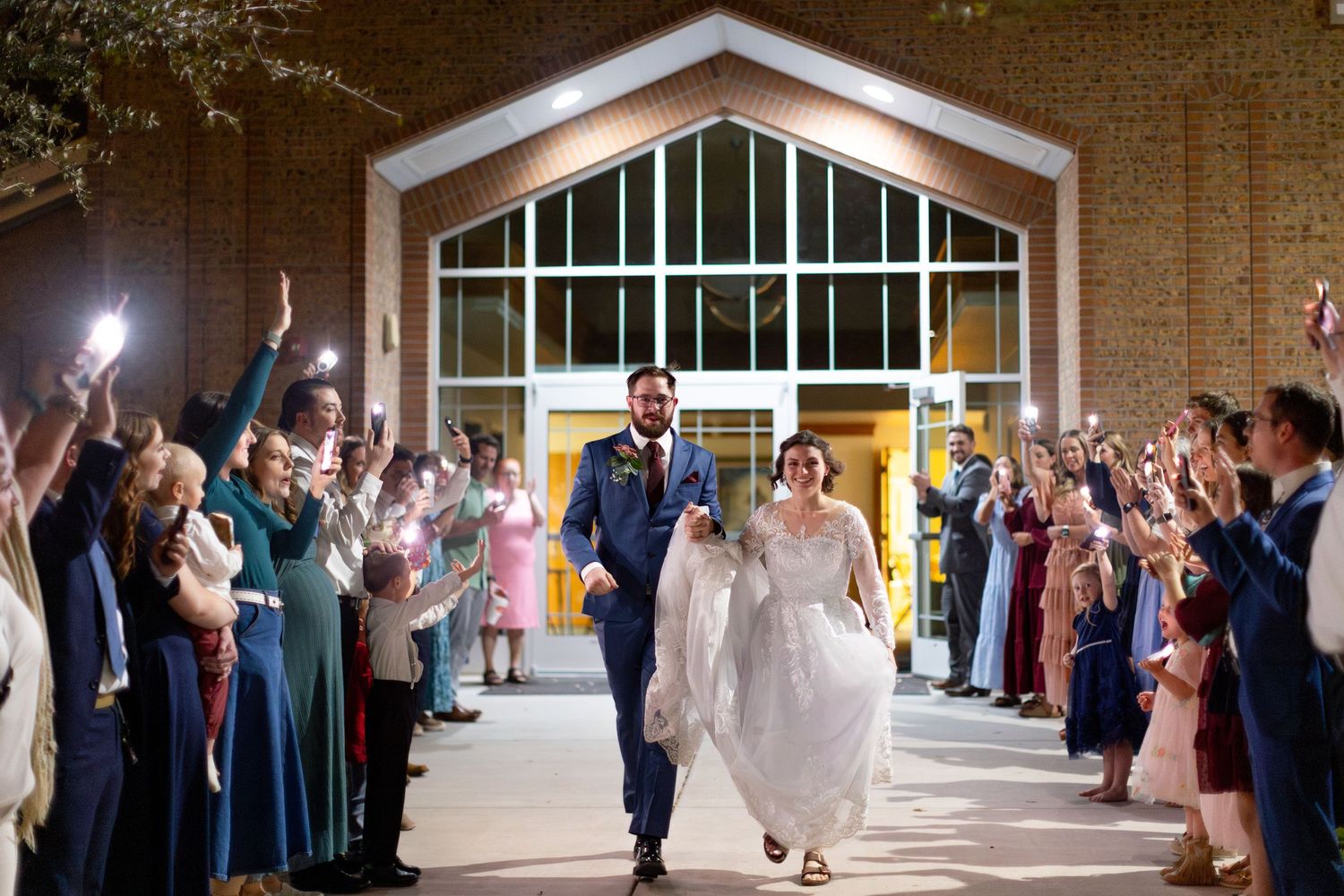 Wedding celebration in a grand hallway with guests lining both sides as couple shares romantic moment.