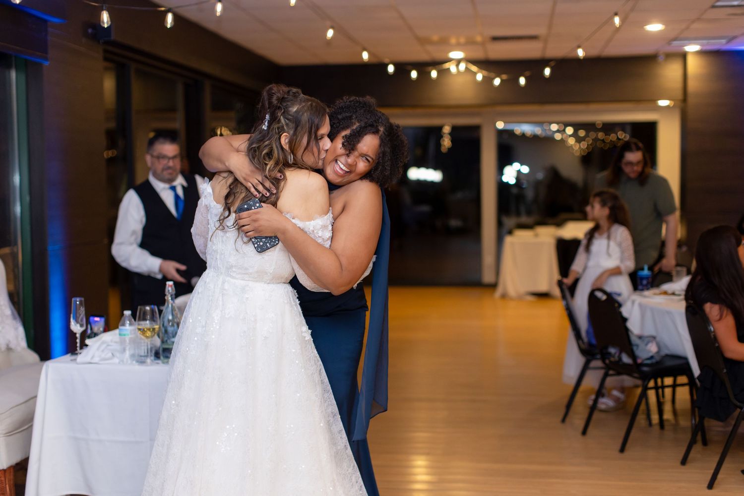 Two brides share an emotional first dance embrace at their wedding reception in a warmly lit venue at Shugrues in Lake Havasu