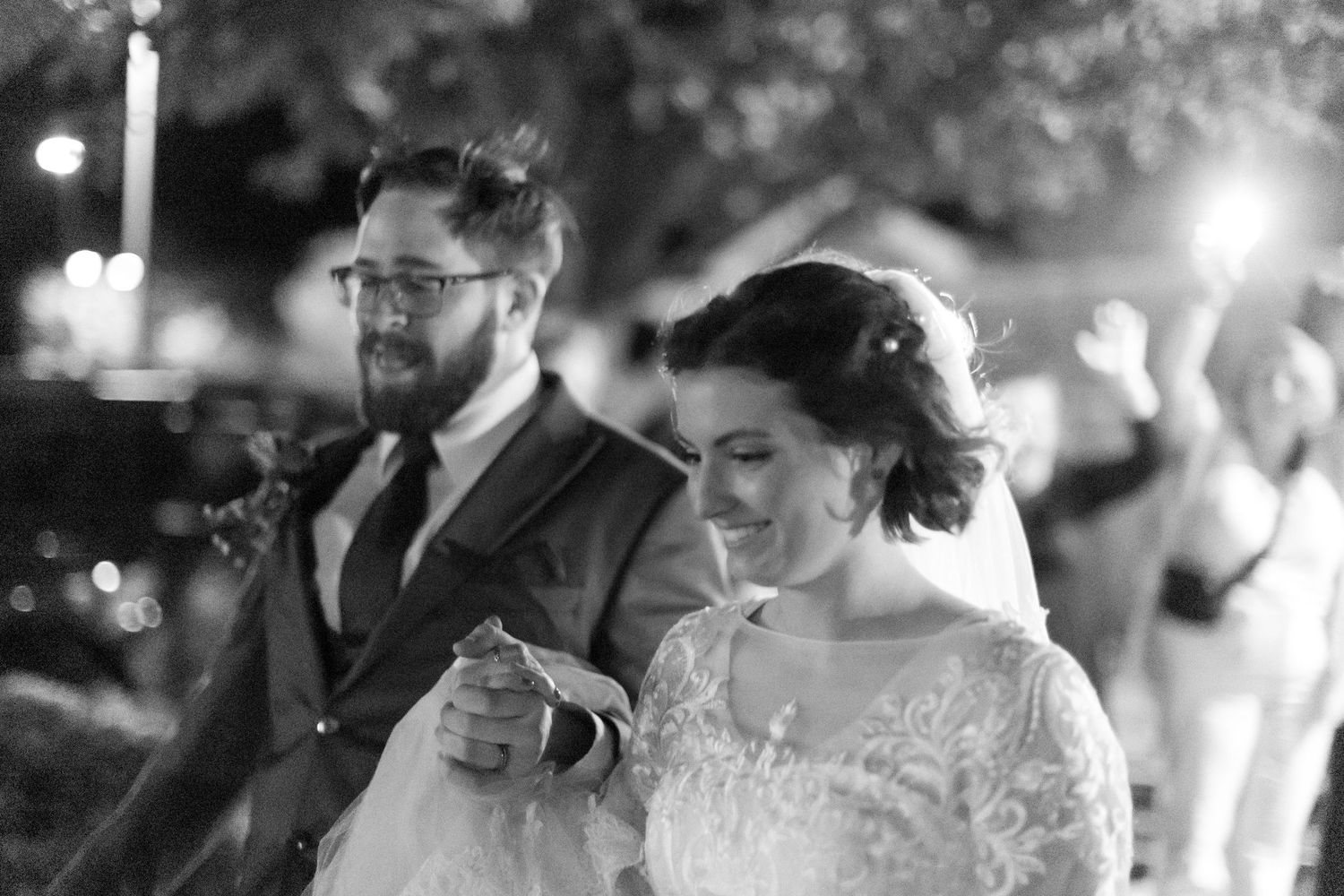 Black and white candid reception photo with bokeh lighting effects.