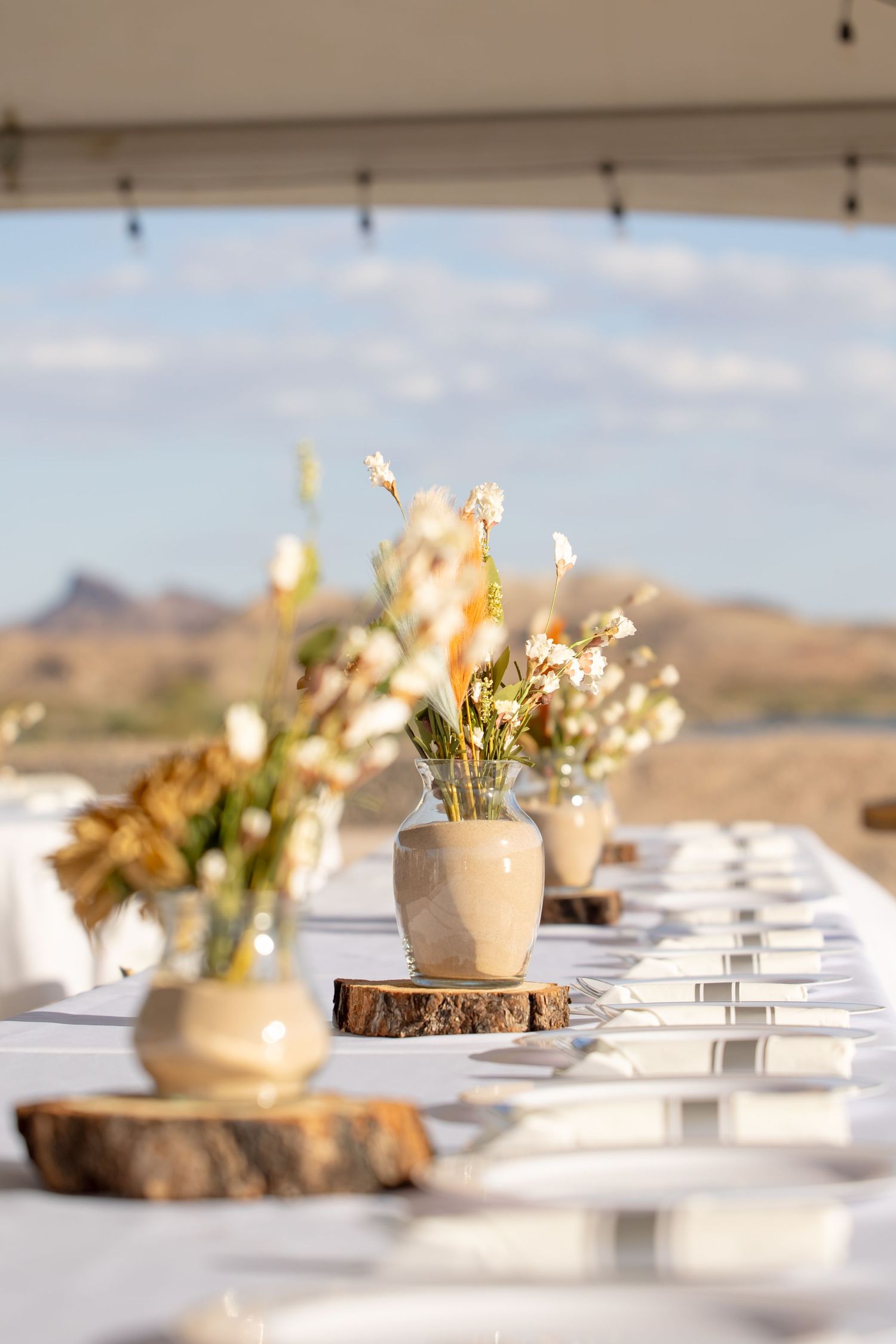 Desert mountain backdrop frames elegant table settings with mason jar flower centerpieces on wooden slices in Lake Havasu City Arizona