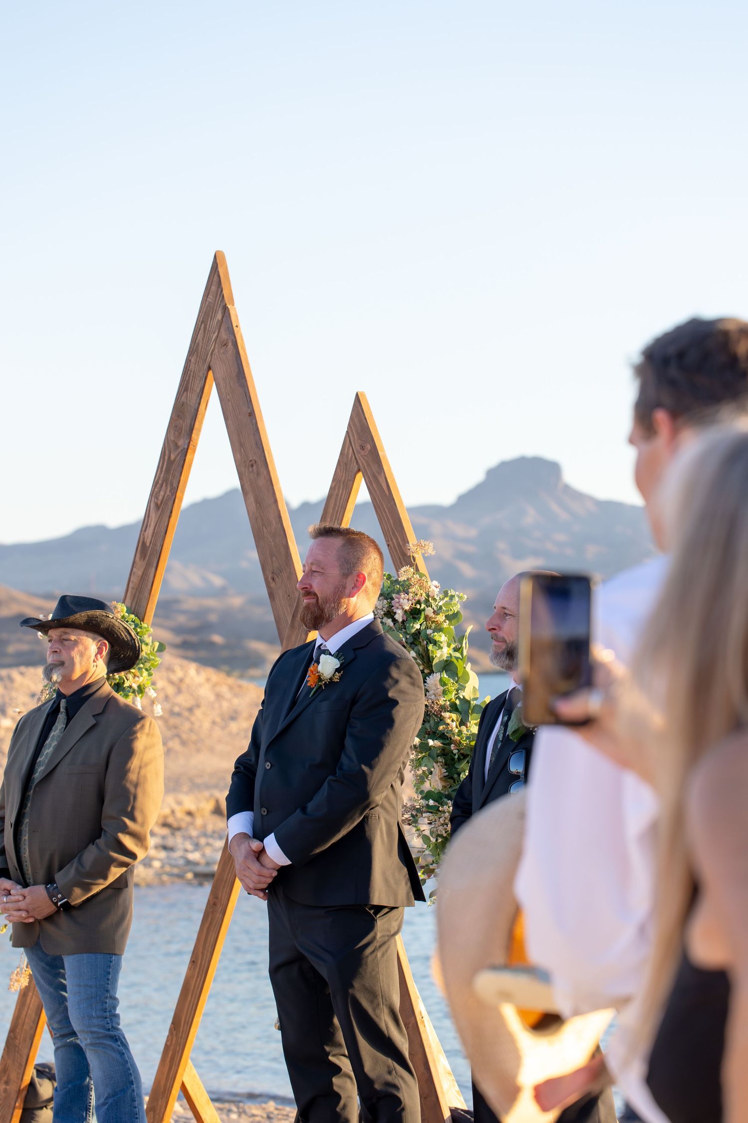 Outdoor wedding ceremony with geometric wooden arch, mountain backdrop at The Riviera Marina, Lake Havasu City