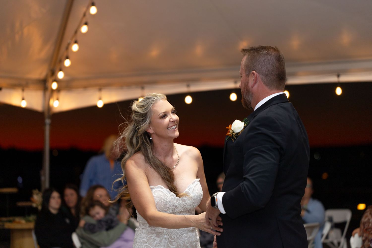 Bride and groom's first dance under tent with string lights at evening reception, The Riviera Marina.