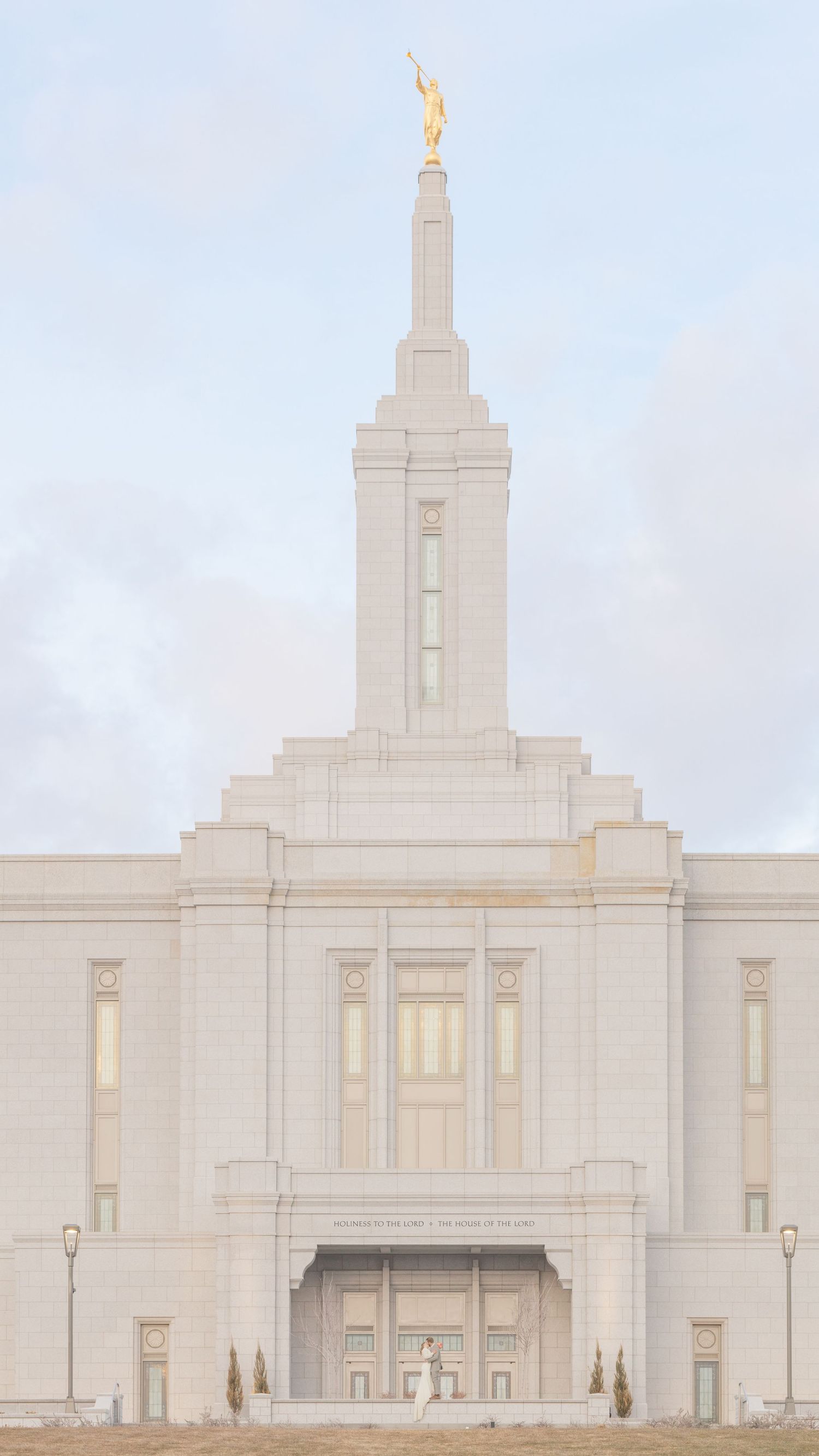 White Mormon temple building with spires photographed against cloudy sky.