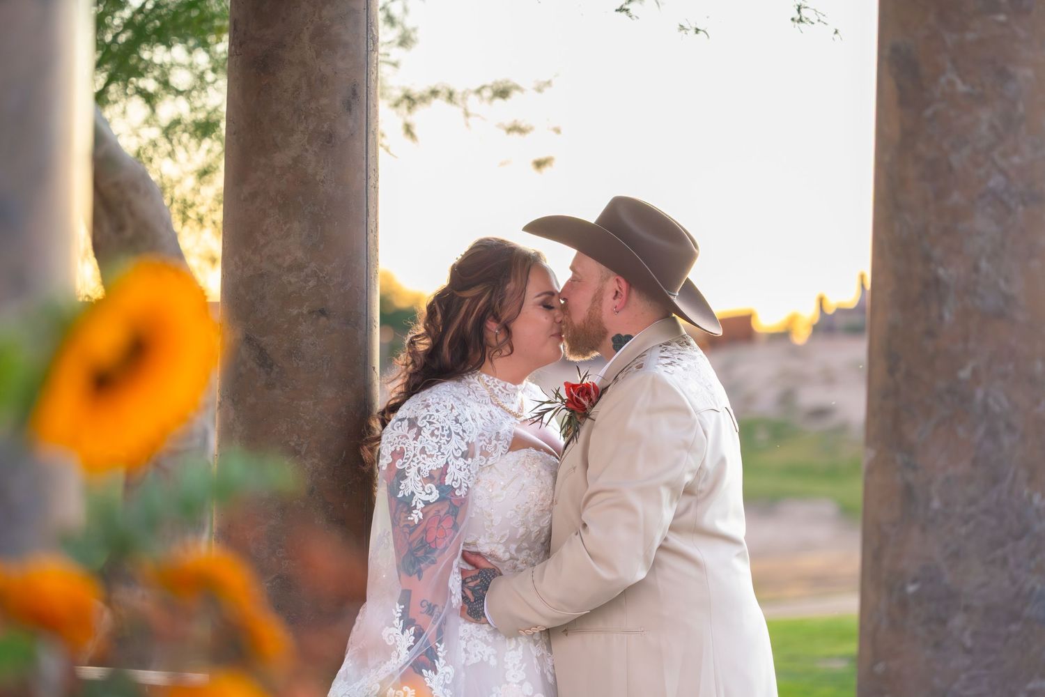 Intimate wedding moments photographed between stone pillars with sunflowers adding natural beauty at iron wolf lake havasu