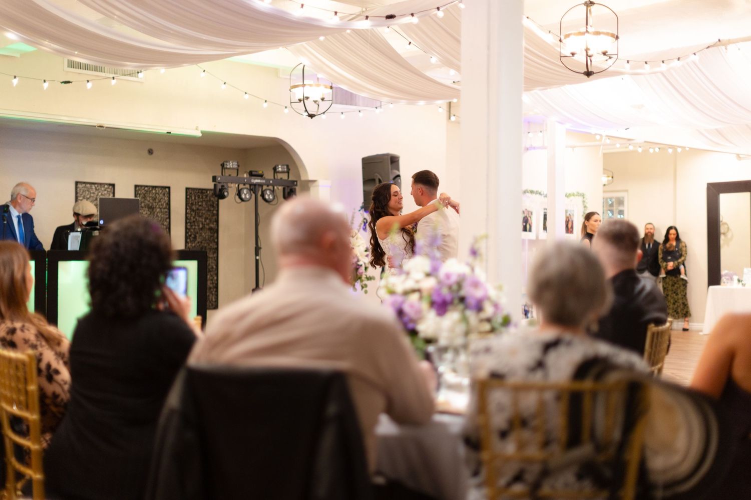 Indoor wedding reception venue with white draping and chandelier lighting.