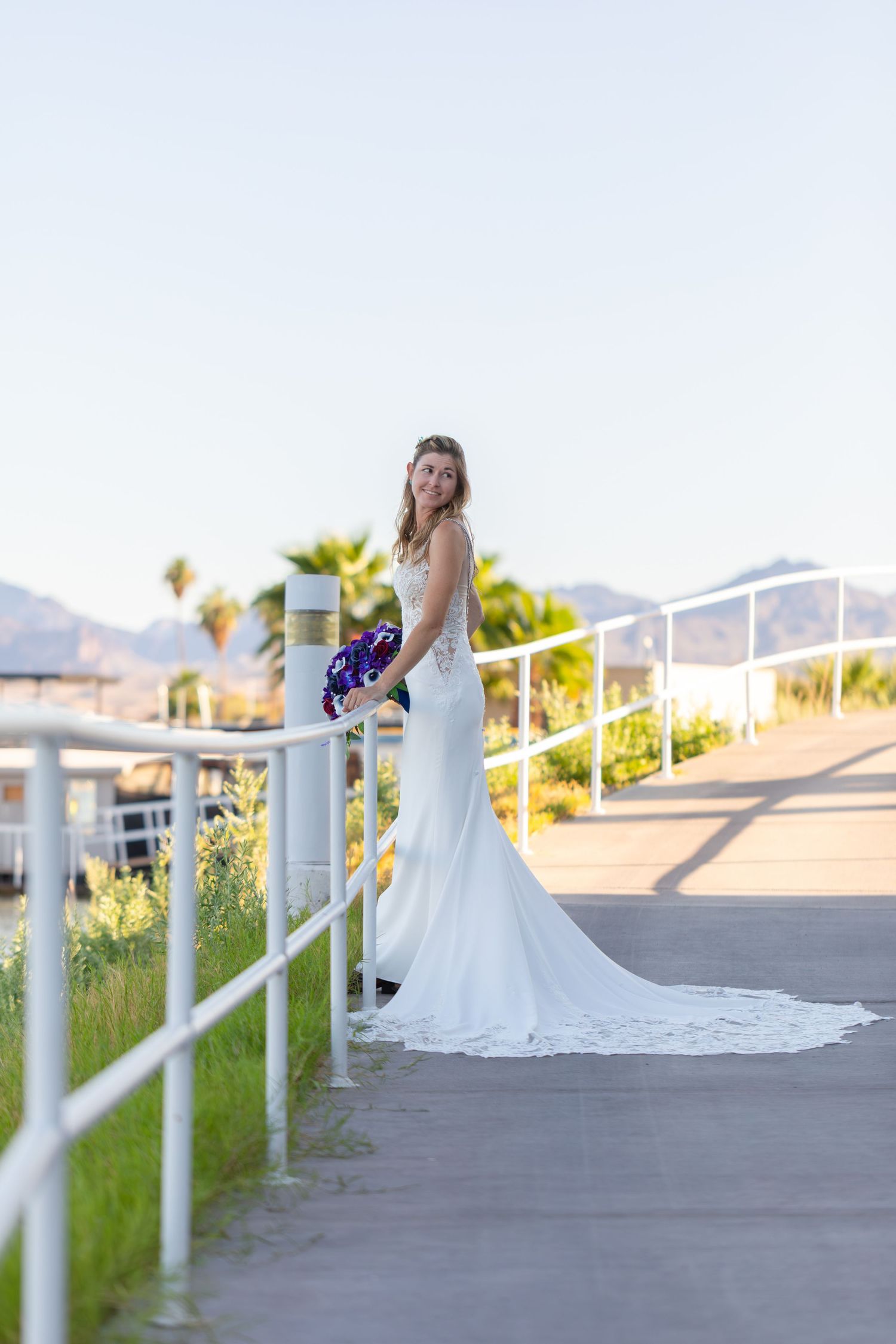Elegant bridal portraits on a paved path with mountain views and white railings.