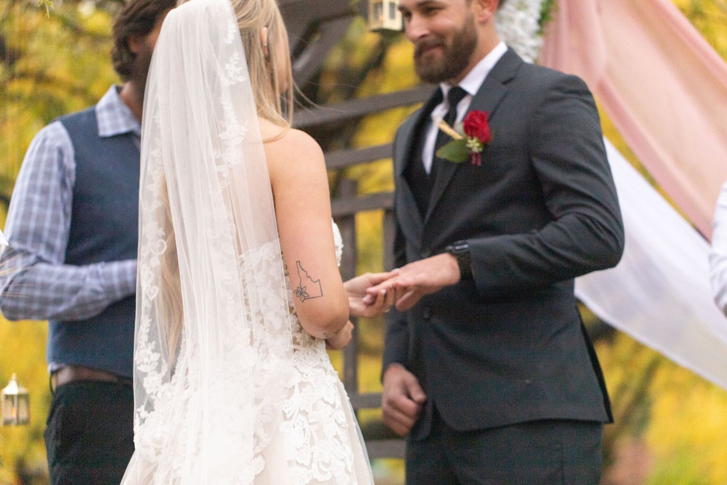 An outdoor wedding ceremony with autumn foliage in the background.